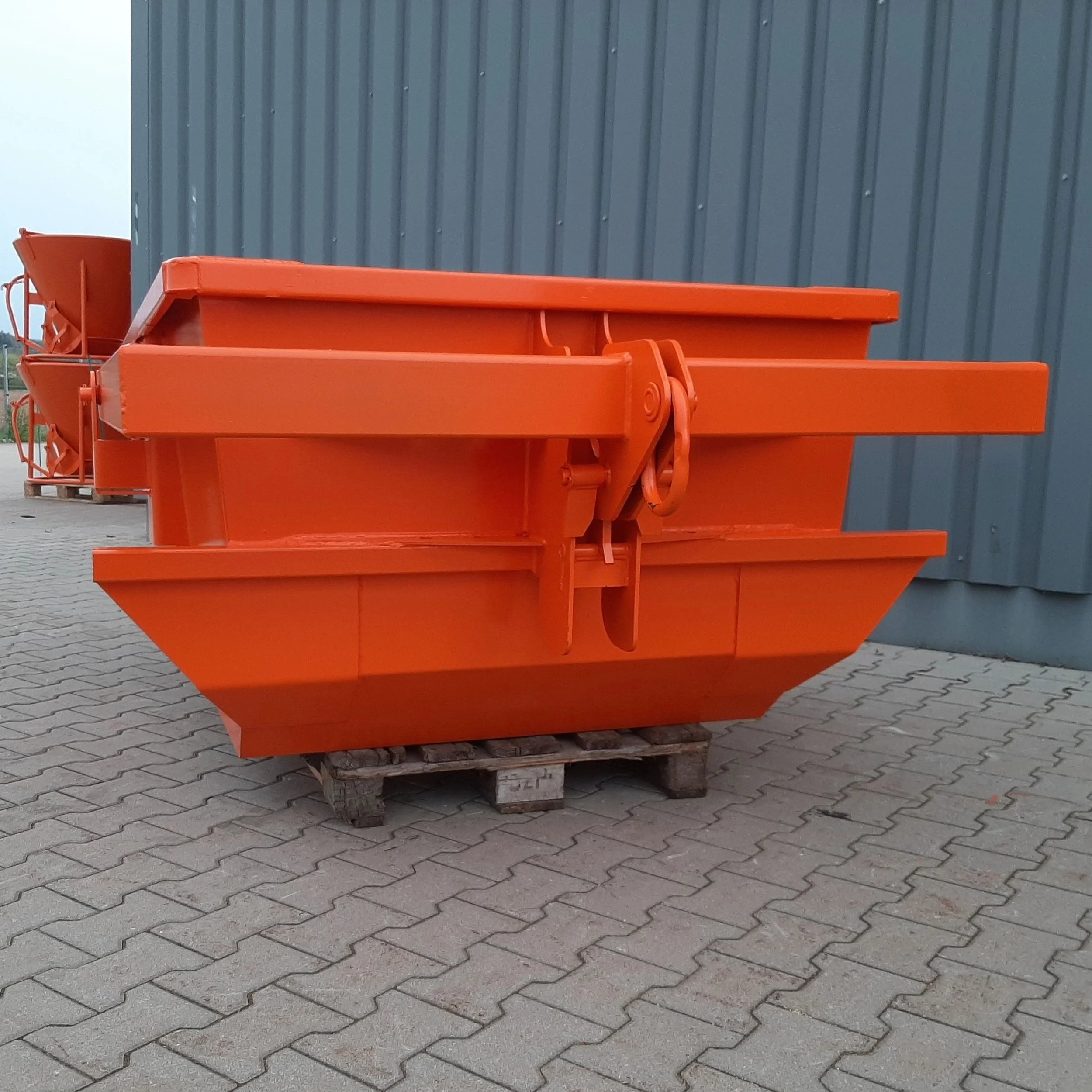 Skip pan lifting equipment at 2.6 yard capacity. Used to transport materials in construction. with equipment. It is orange in color and at the factory..
