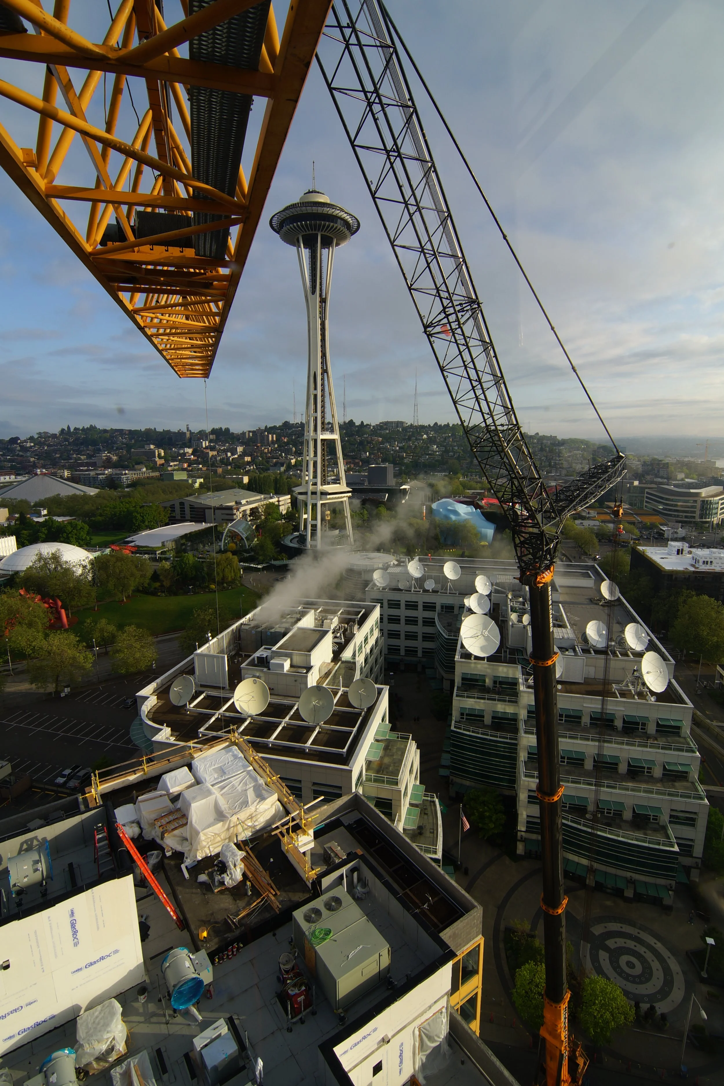 Mobile crane dismantling a tower crane with the space needle in Seattle as the background