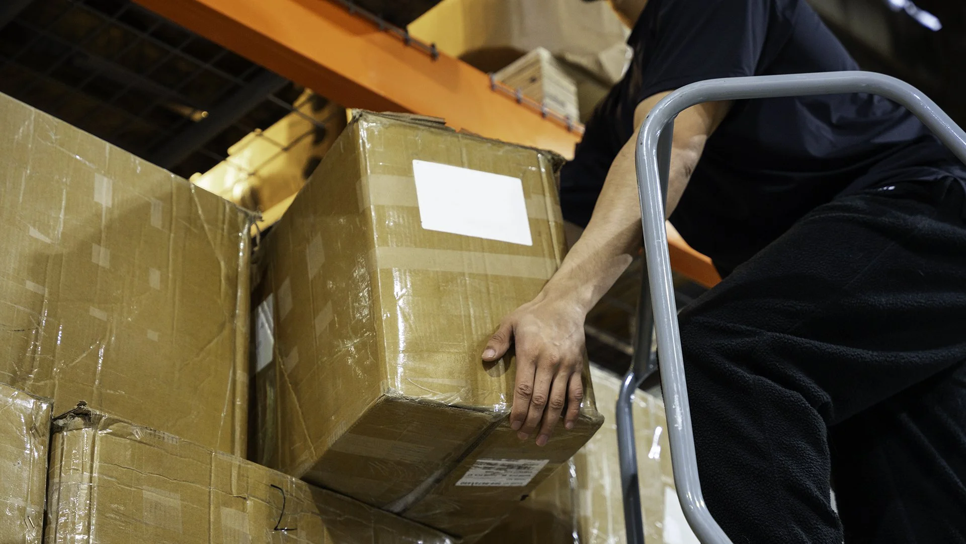 Person lifting cardboard box in warehouse