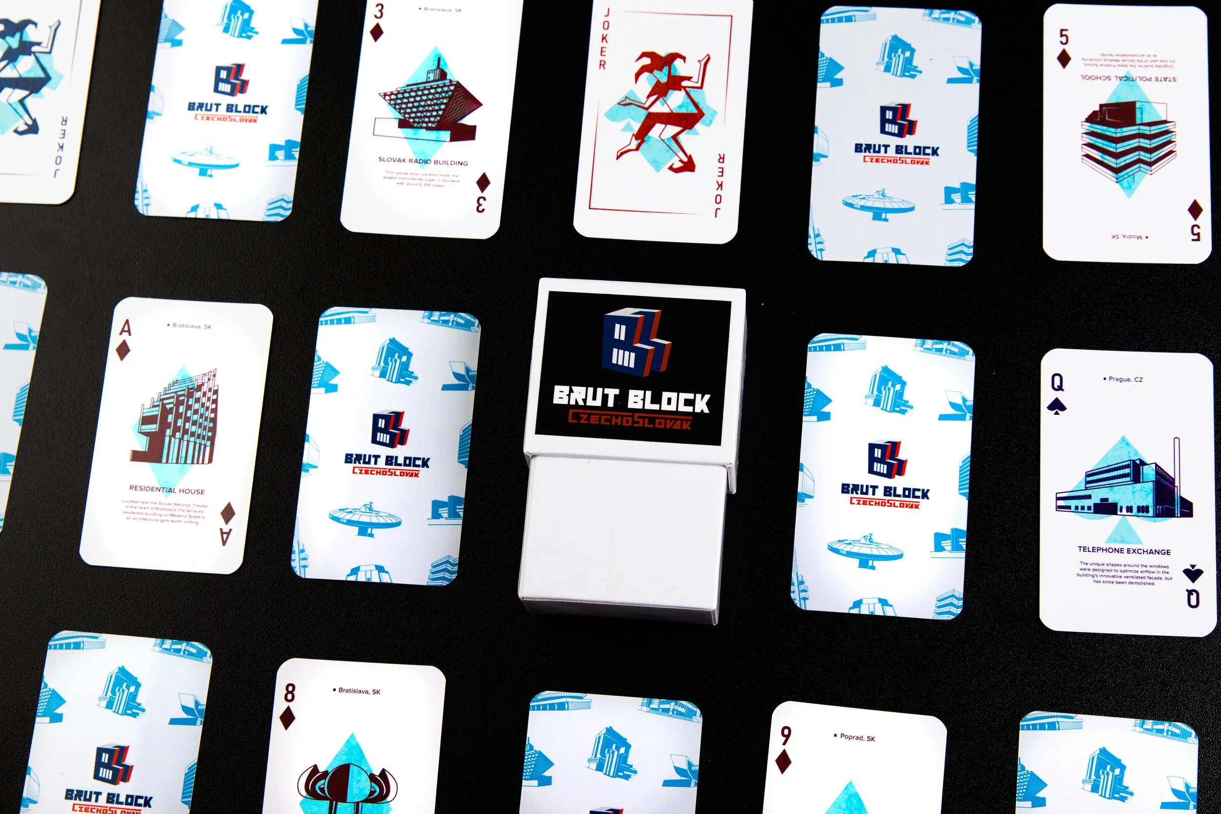 A deck of playing cards on a black surface, featuring artwork of buildings and landmarks, with the 
