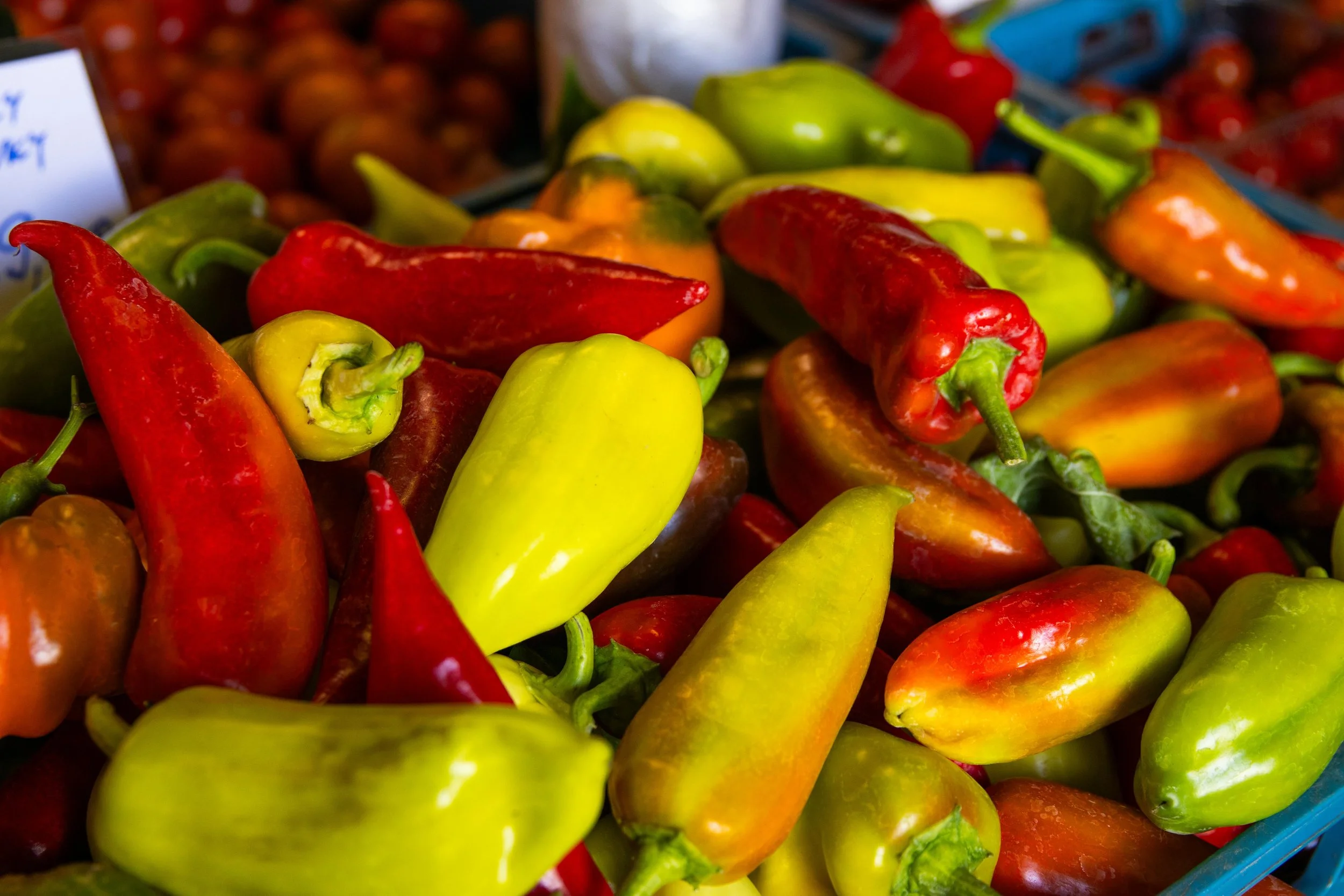 Various colorful peppers, including red, yellow, and green, displayed in a market.