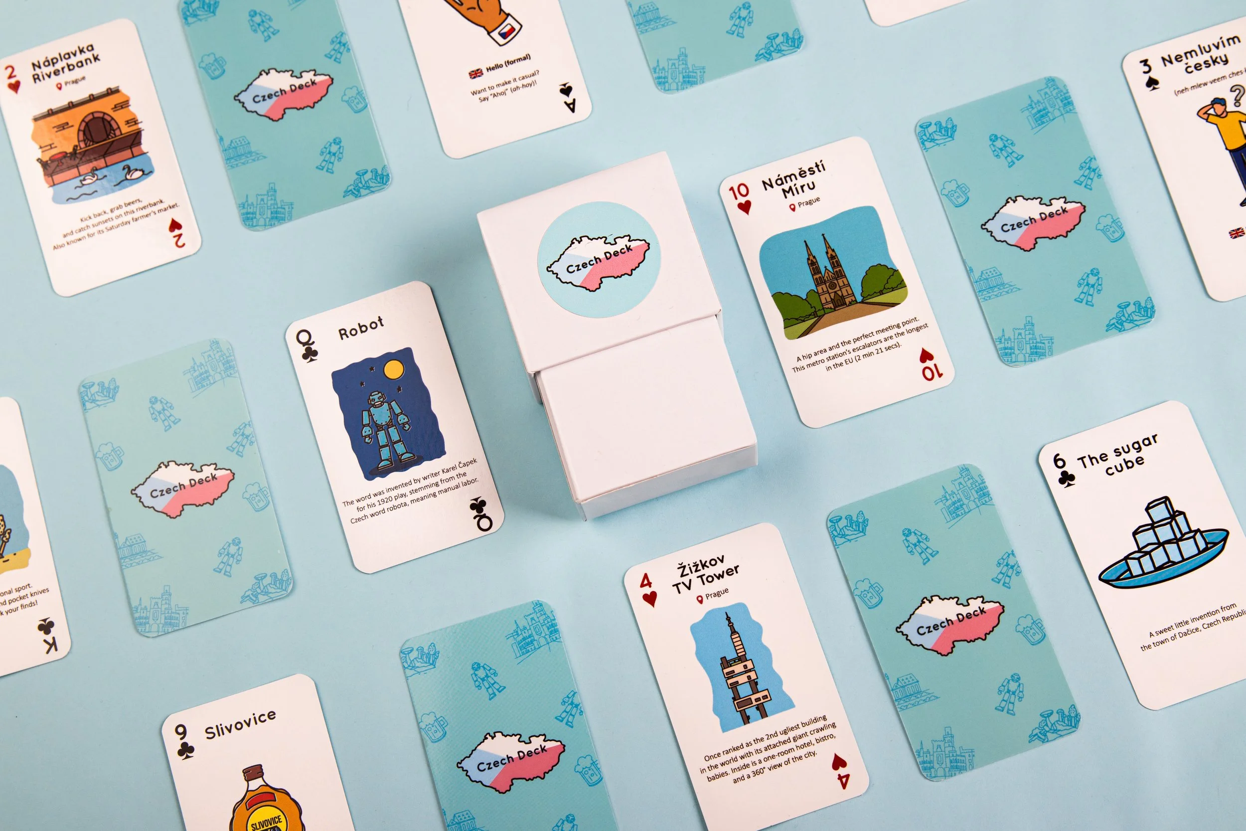 Playing cards themed around Czech landmarks and symbols, laid out on a light blue surface.