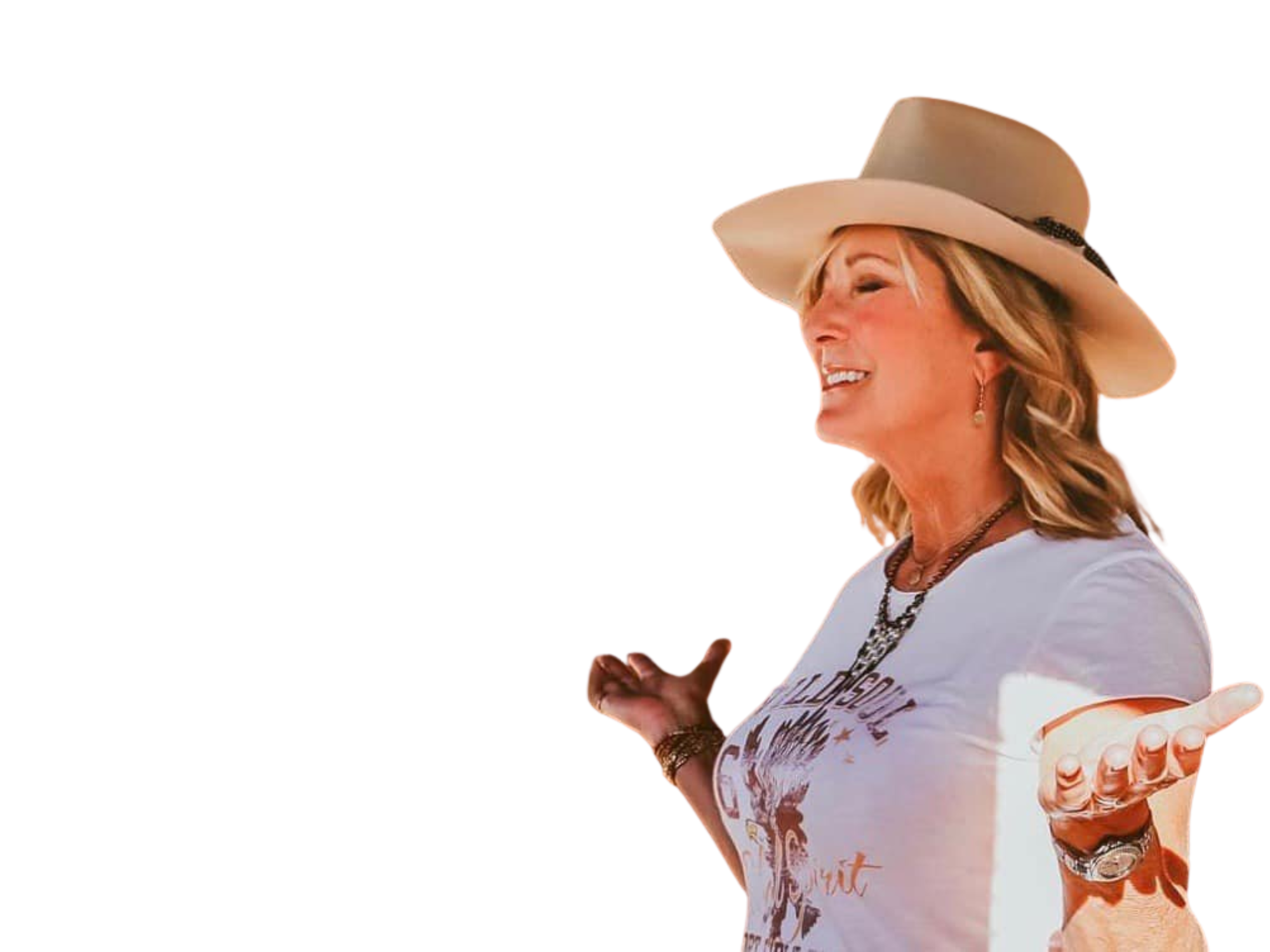 Robin Gerblick wearing a beige hat and a white graphic t-shirt is smiling and gesturing with her hands. She is adorned with necklaces and bracelets.