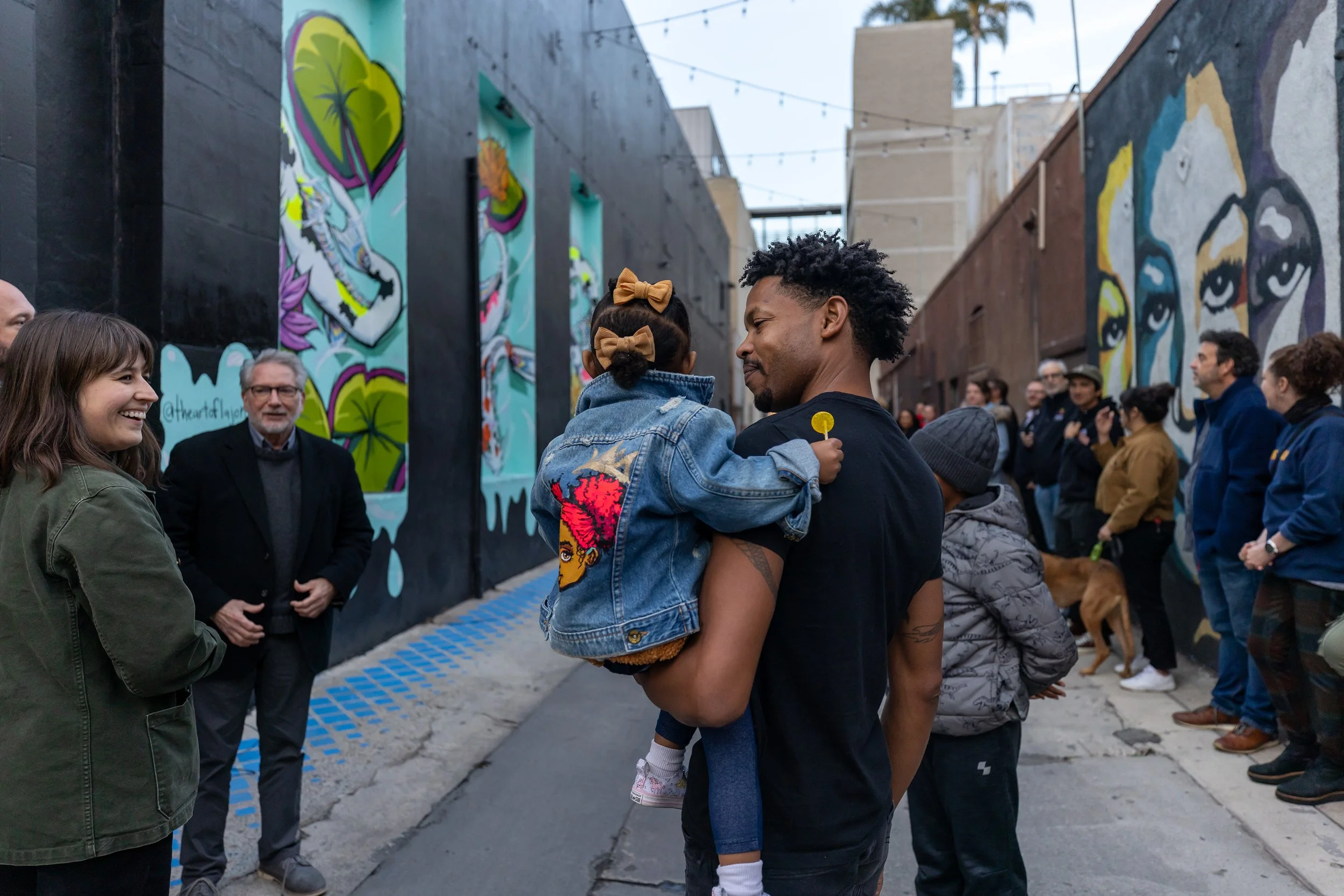 Artist LaJon Miller celebrates the unveiling of his mural in downtown Long Beach with family and friends. The mural panels include solar-based lighting which provides light to a once dark and unsafe alley in downtown.