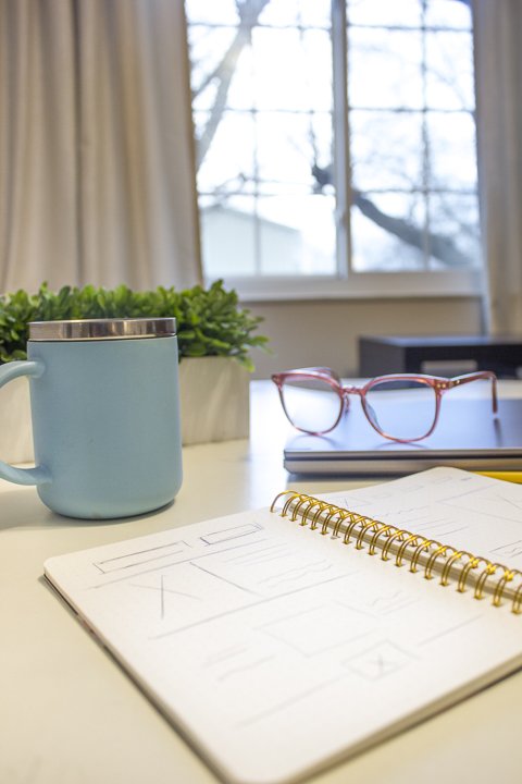 coffee mug and notebook of web design sketches