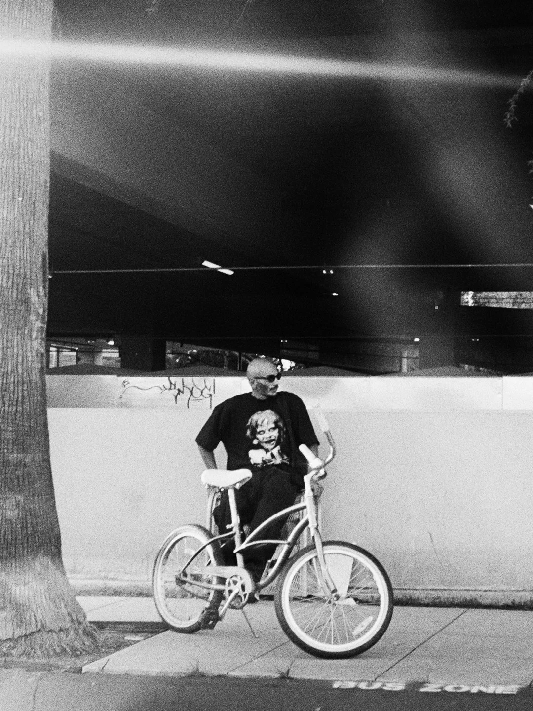 man next to lowrider style bicycle waiting at a bus stop