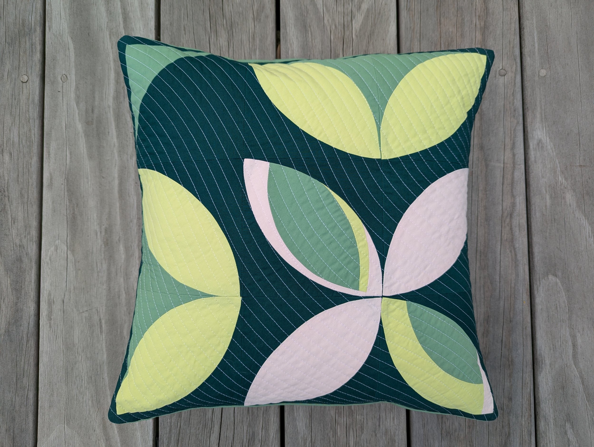 The 5759 Block Pillow in green, pink, and yellow colors with curved petals