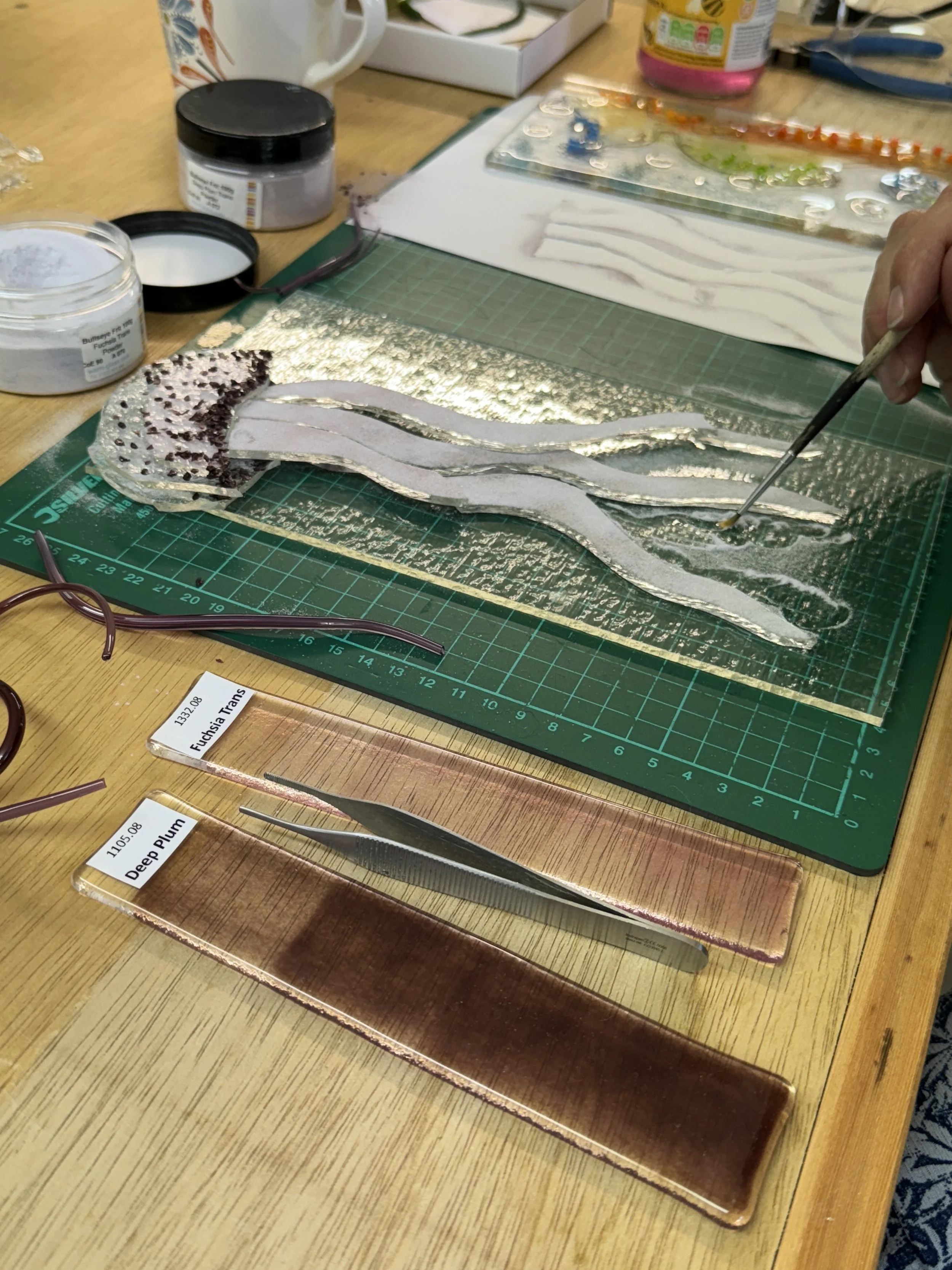 Artist creating a glass jellyfish on a cutting mat with glass powders and tools