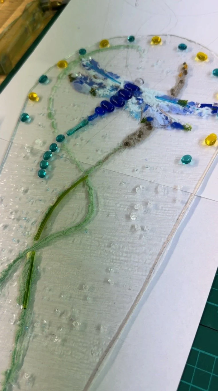 Glass artwork featuring a dragonfly and colored beads