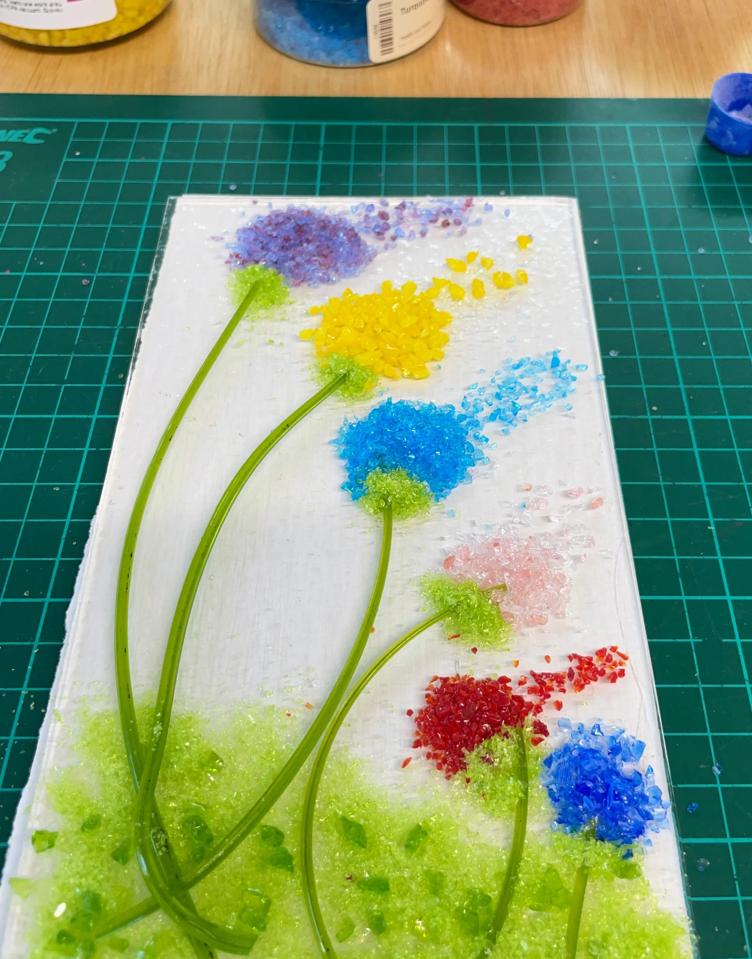 Glass art with colorful flowers on green grid cutting mat
