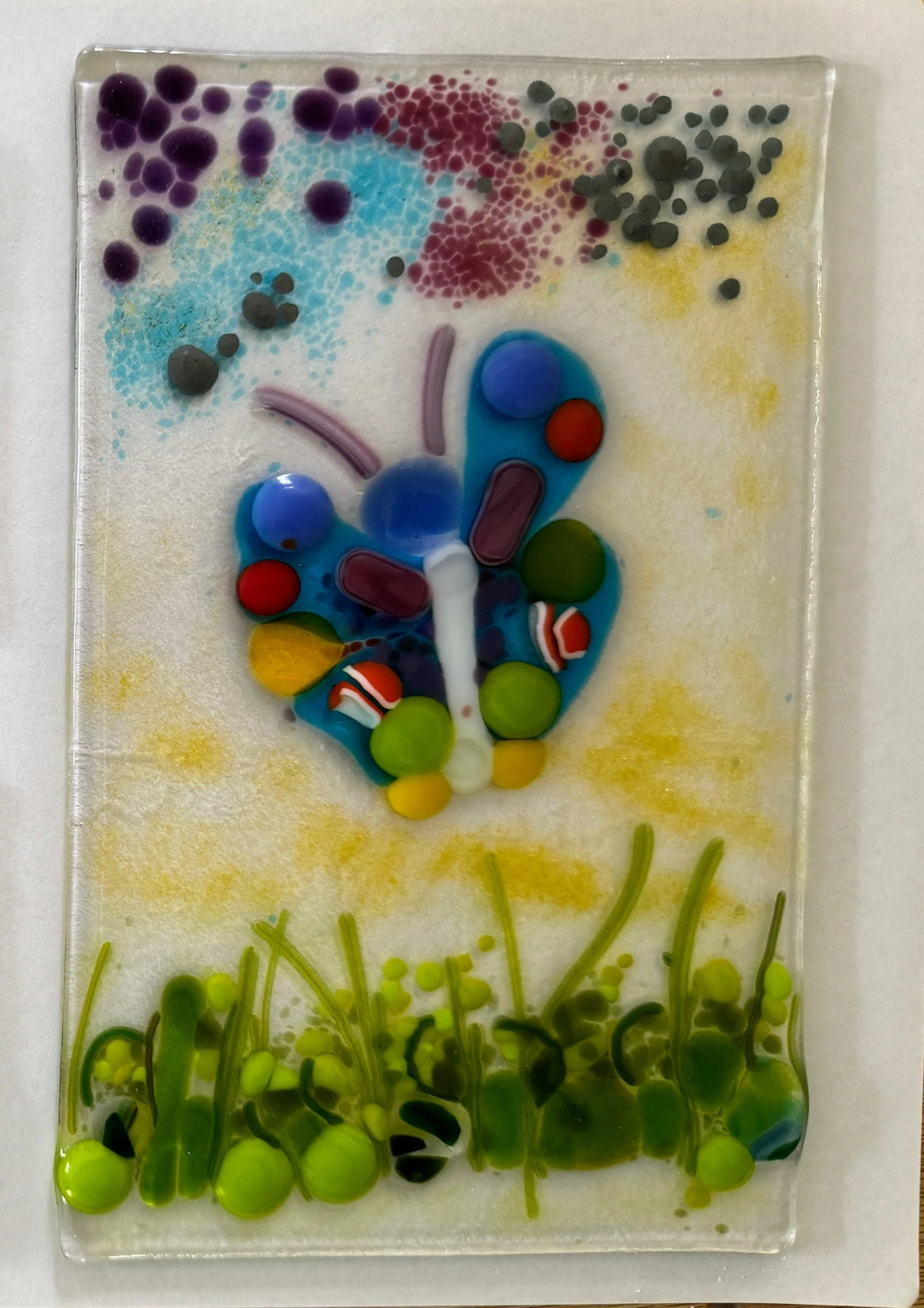 Colorful glass artwork featuring a butterfly with abstract surroundings