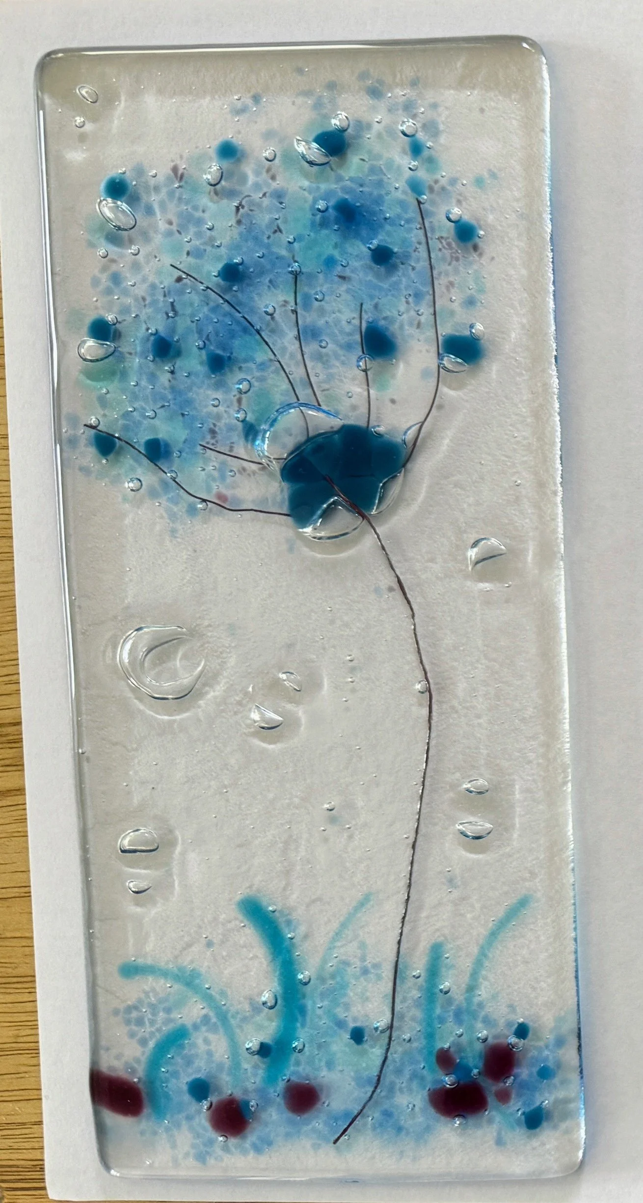 Artistic glass art panel with abstract blue and red design, resembling flowers or nature elements.