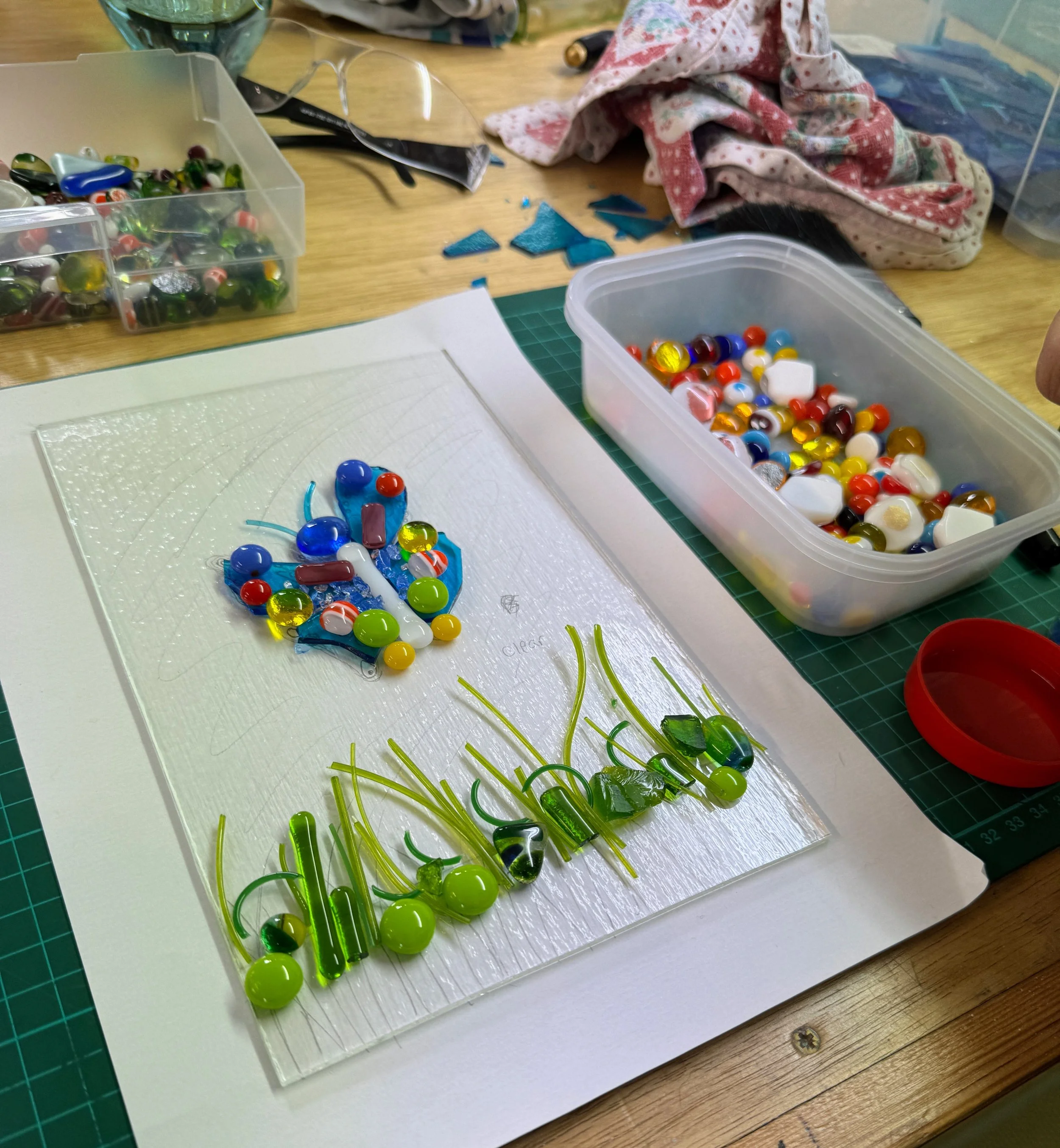 Glass art project in progress with colorful glass pieces on a work surface.