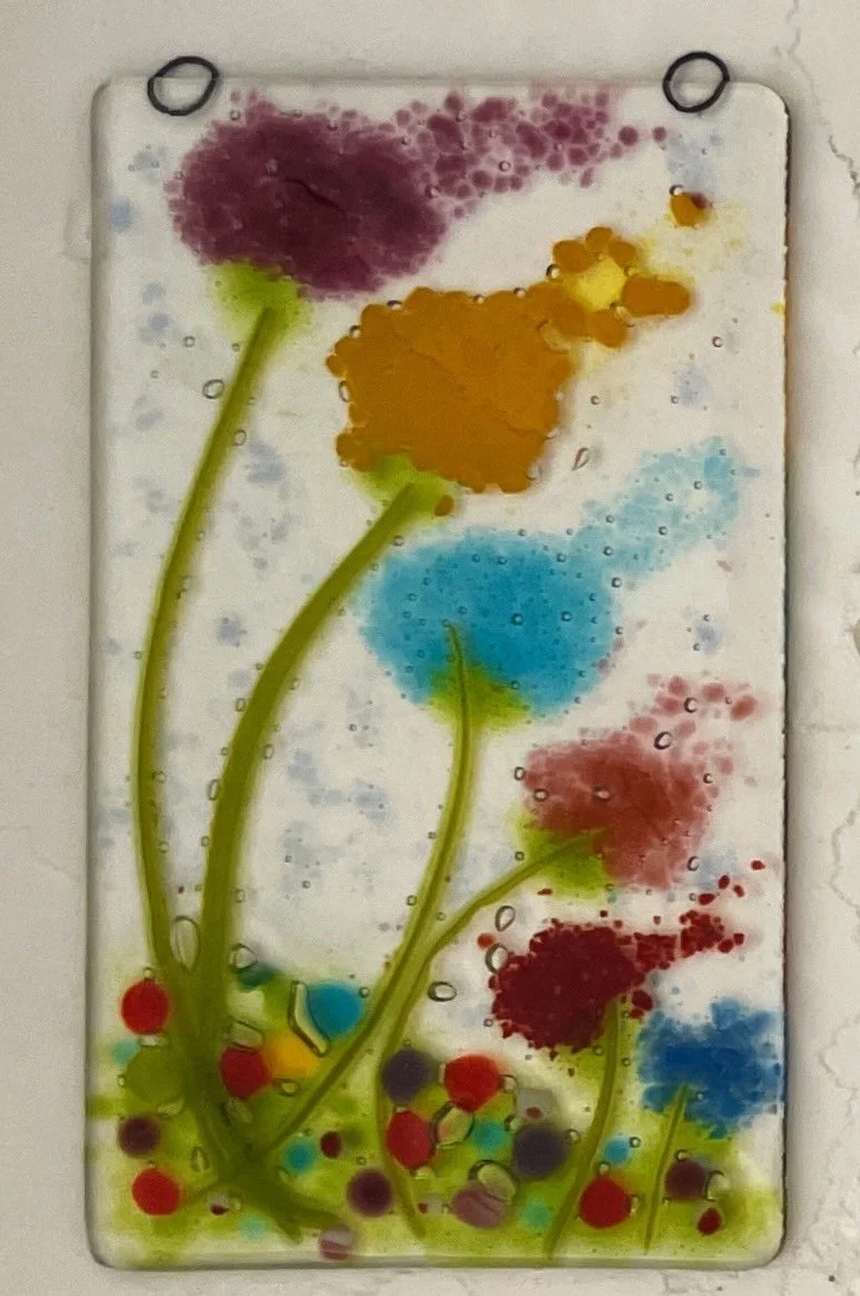 Colorful abstract floral glass art with yellow, blue, and red flowers on green stems