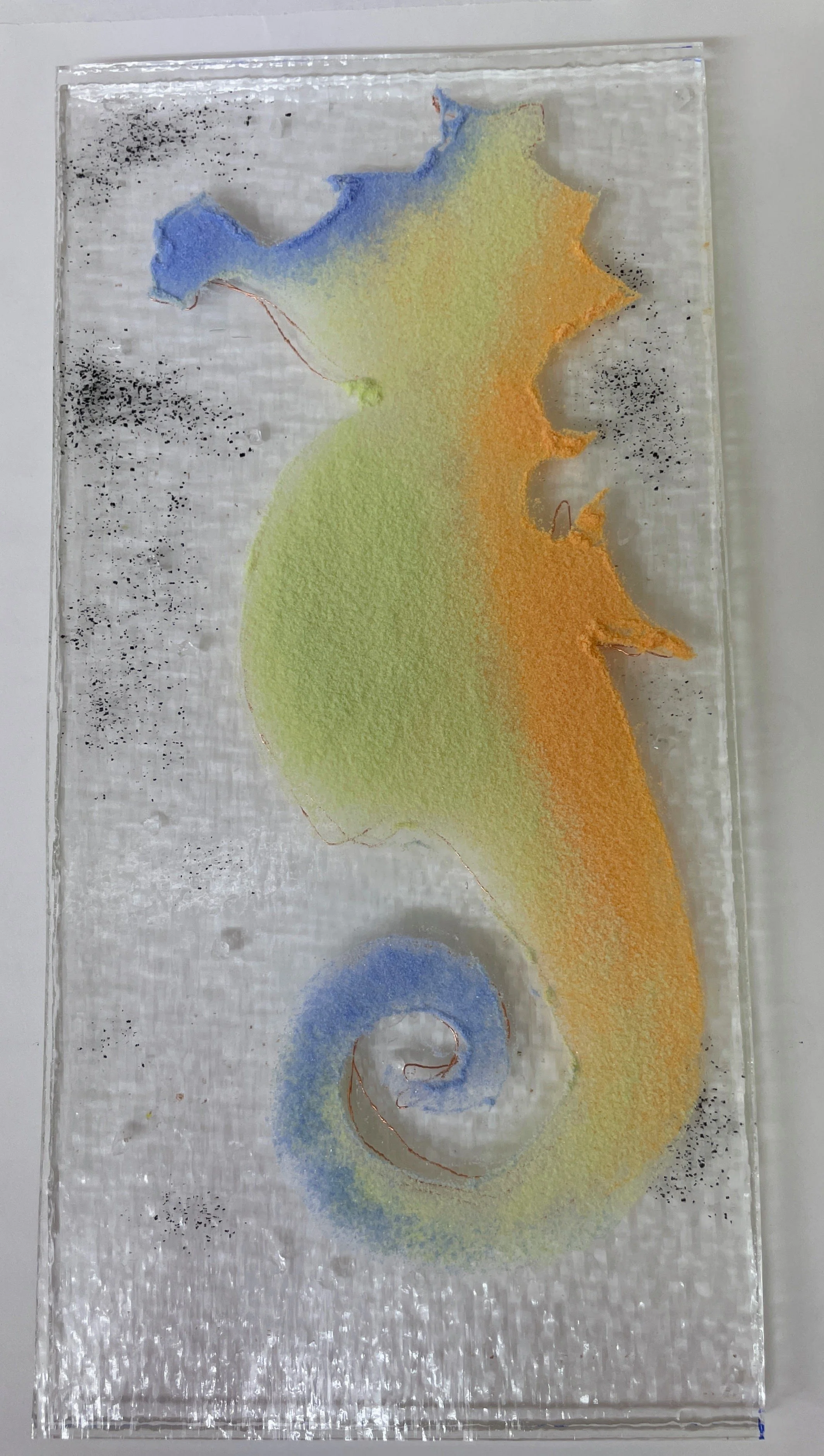 Colorful seahorse art on glass with blue, orange, green, and yellow hues