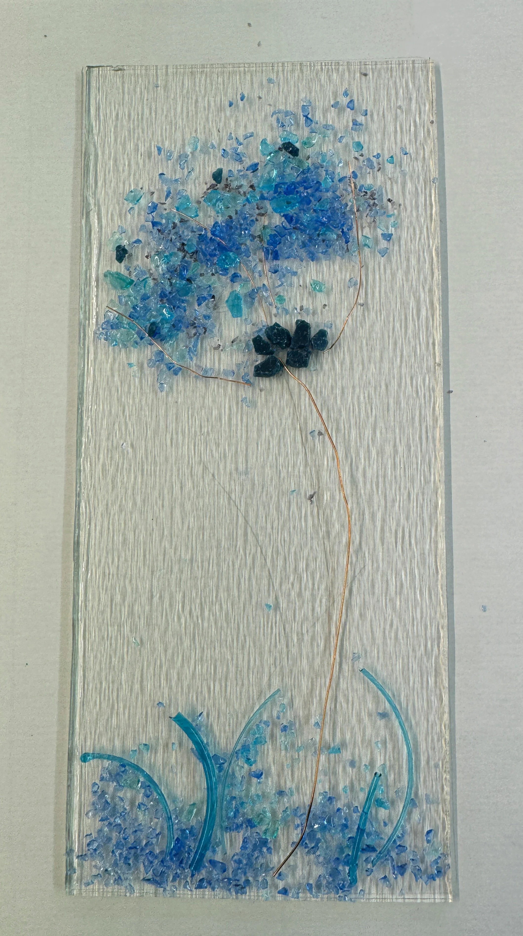 Glass art with blue tree and grass design