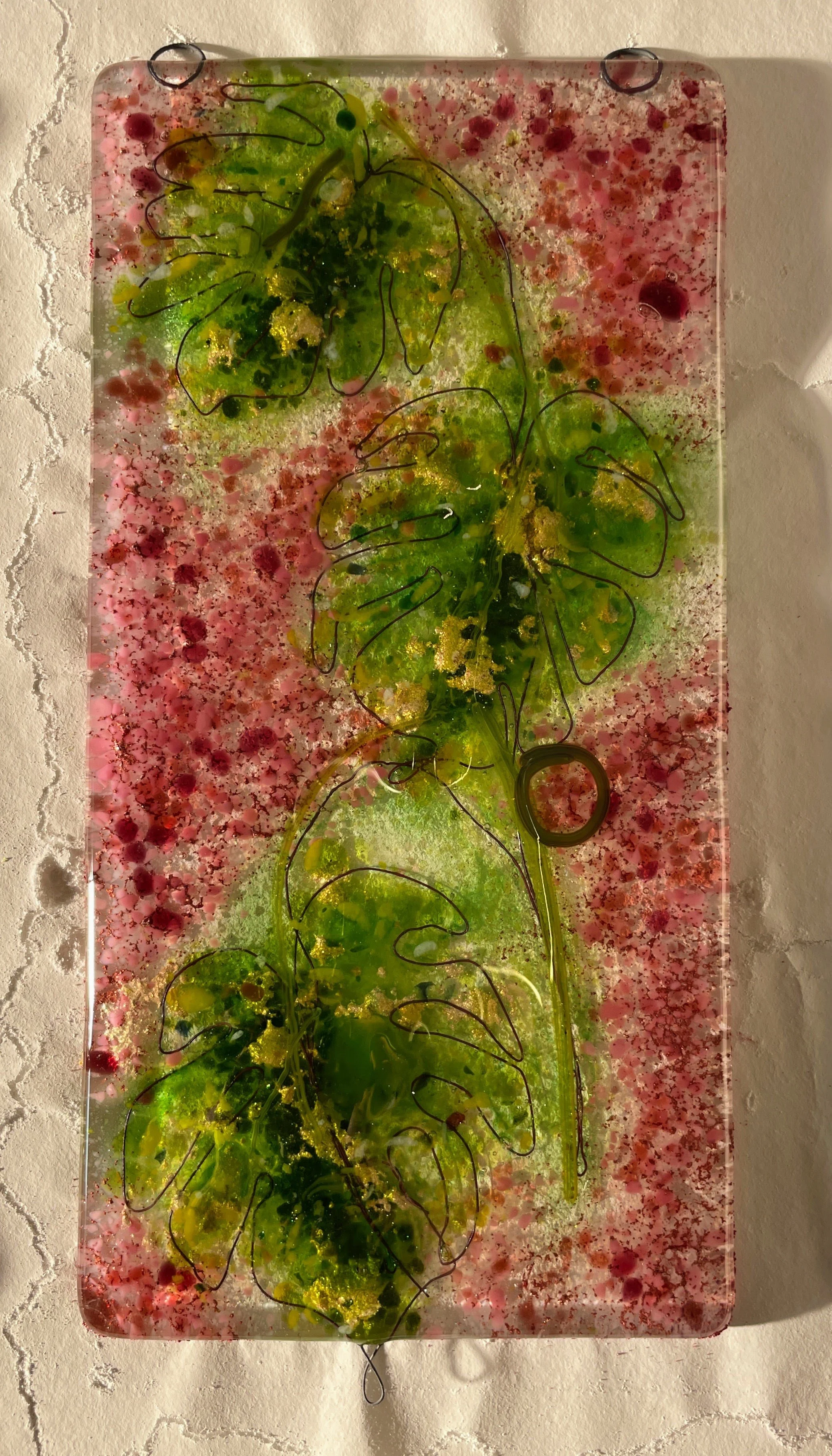 Glass art panel with green leaf design on pink and white background