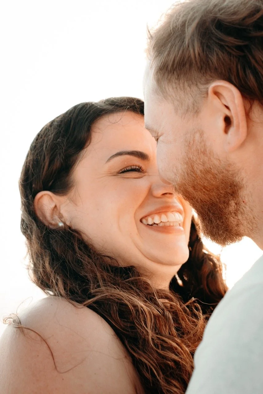 A close-up of a happy couple with their foreheads touching, smiling, and enjoying a tender moment.