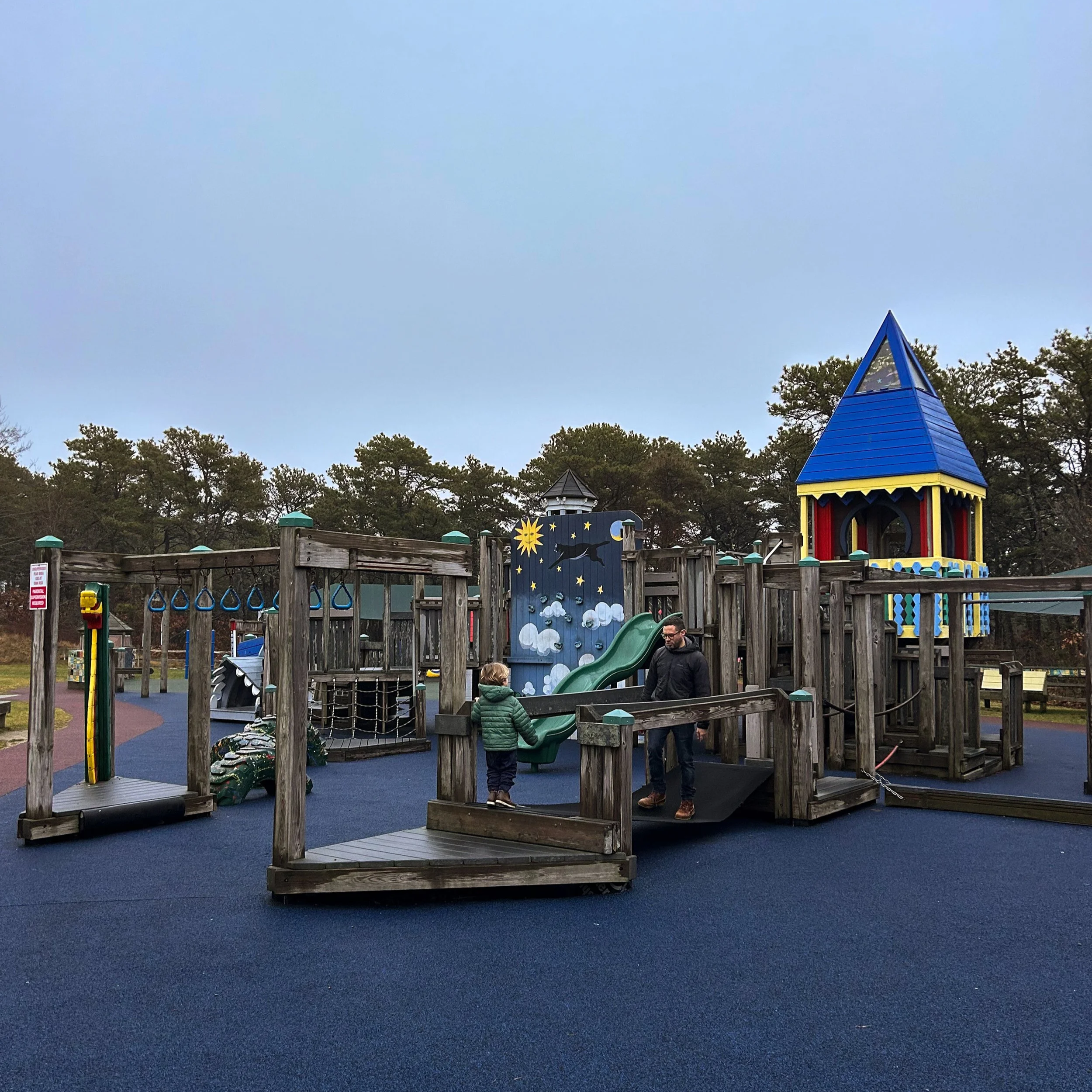 A father and son playing on an old-fashioned wooden playground at Puma Park in Truro on Cape Cod
