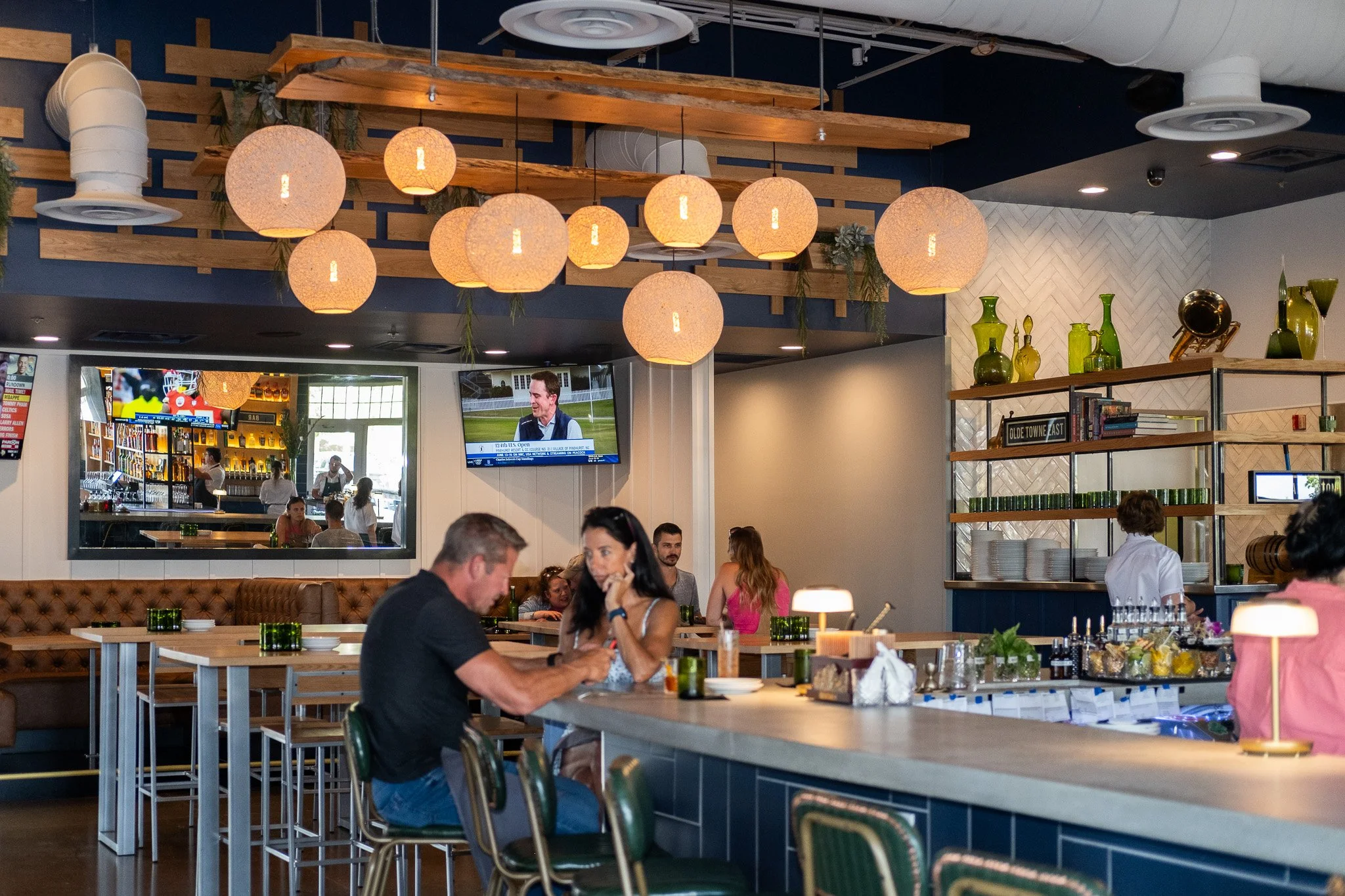 Guests enjoying drinks and conversation inside Liberty Tavern, showcasing the warm lighting, modern tavern design, and inviting bar and dining space.