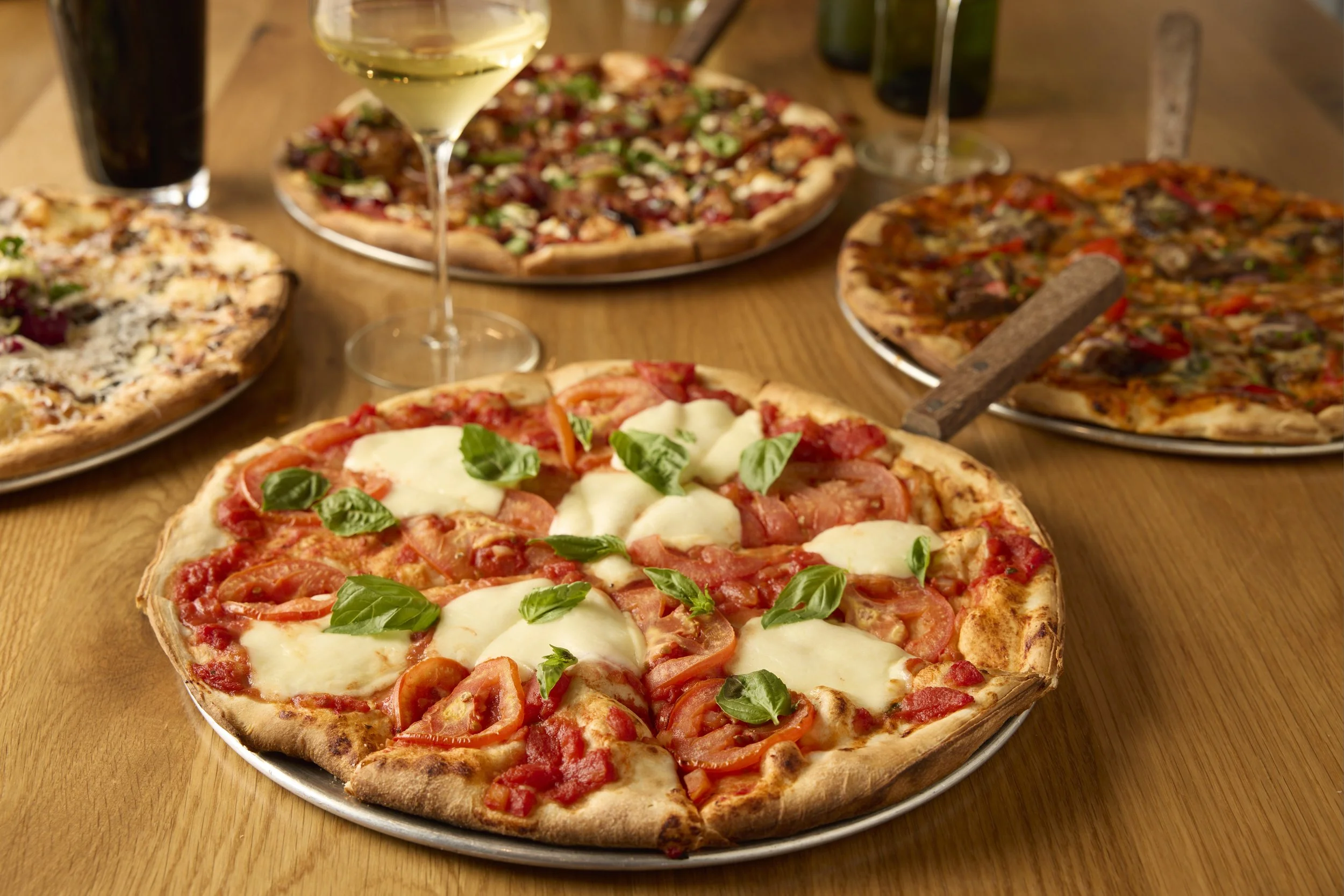Freshly baked artisan pizza topped with mozzarella, tomato, and basil on a table at Liberty Tavern in Polaris, Ohio.