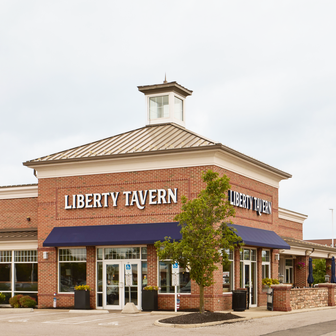 Exterior of Liberty Tavern Polaris, an elevated American tavern with brick façade, navy awnings, and a welcoming neighborhood atmosphere.