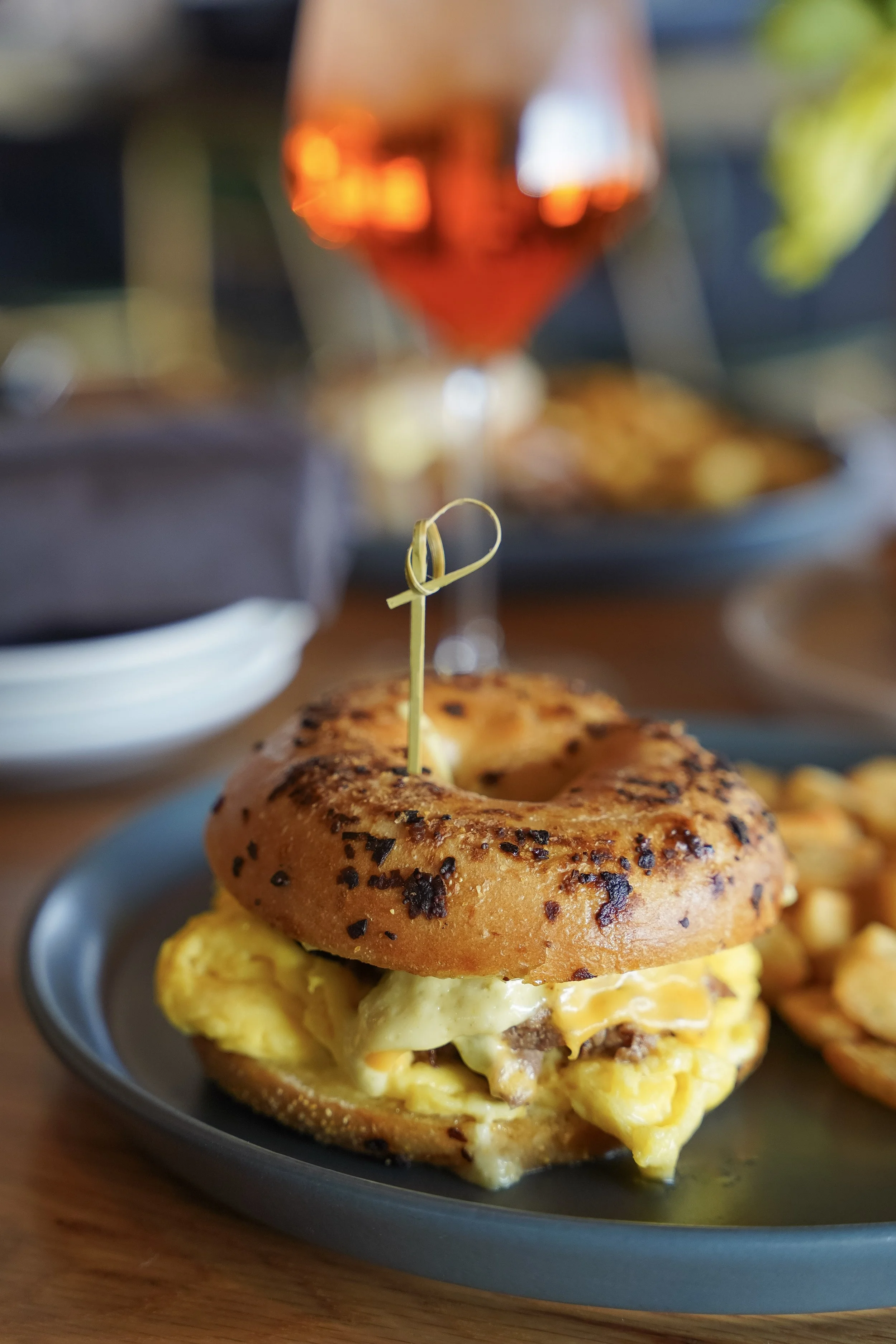 Brunch sandwich on a toasted everything bagel with scrambled eggs, melted cheese, and breakfast sausage served at Liberty Tavern in Polaris, Ohio.