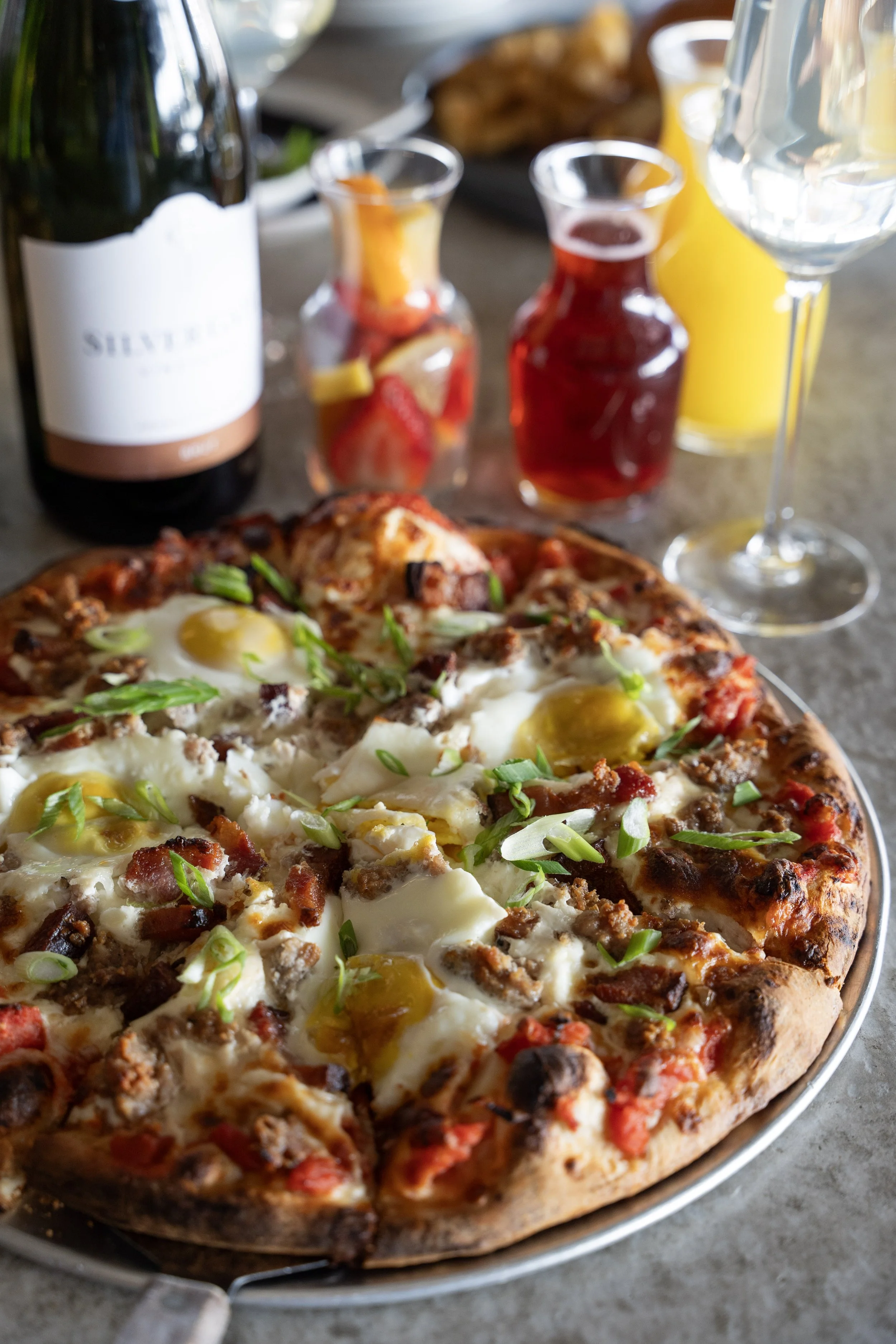 Breakfast pizza topped with over-easy eggs, sausage, bacon, mozzarella, and green onions at Liberty Tavern brunch in Polaris, Ohio.