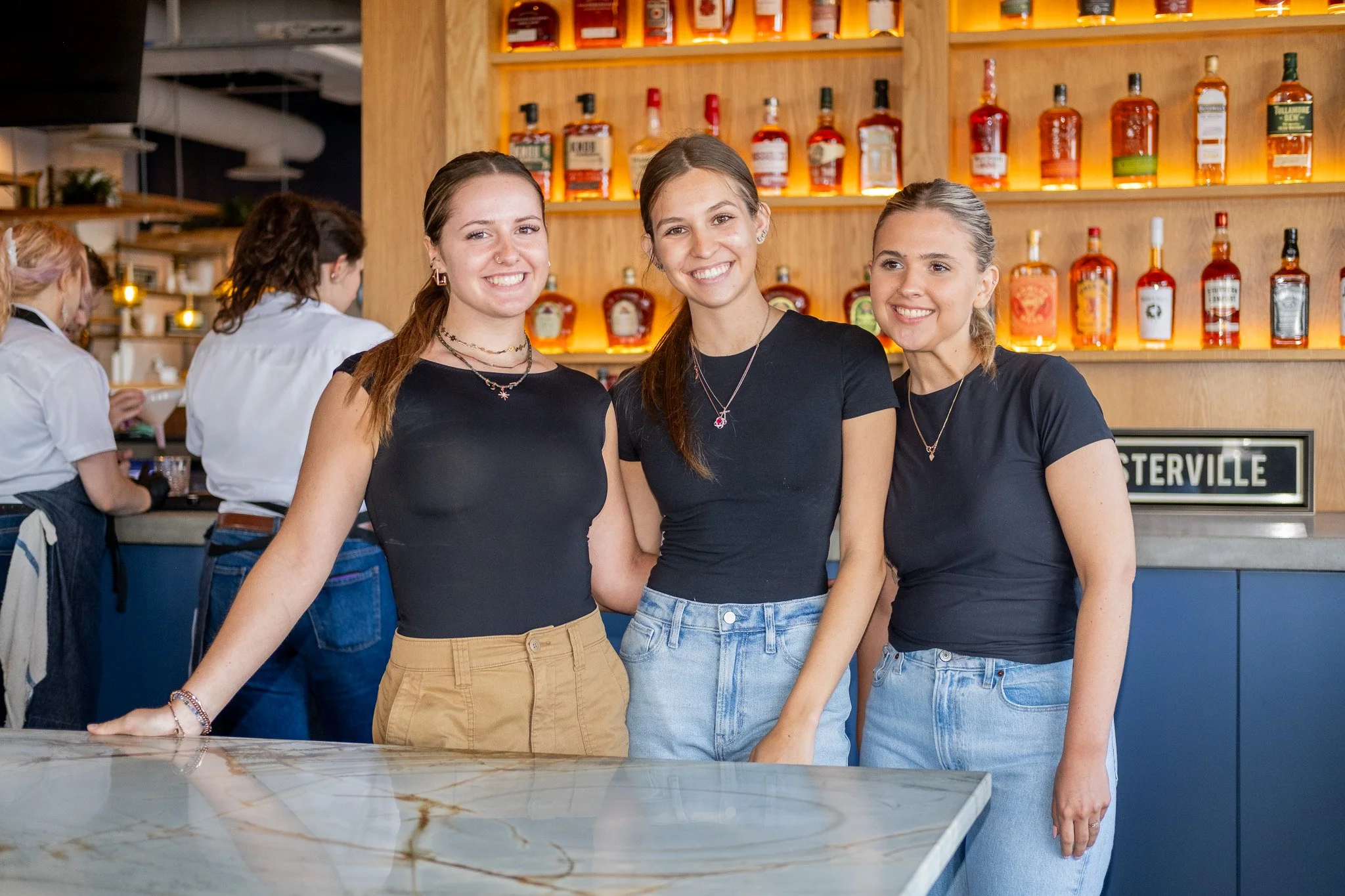 Smiling Liberty Tavern team members standing behind the bar at Liberty Tavern Polaris, reflecting the welcoming and community-focused tavern atmosphere.