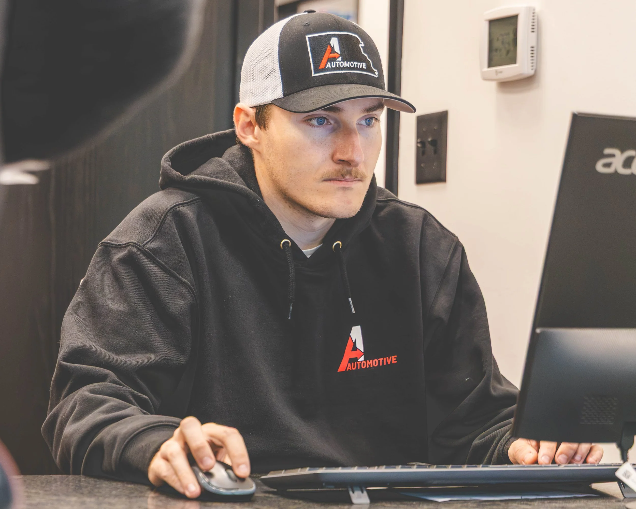 A1 Automotive technician at work wearing a screen printed Carhartt shirt and an embroidered hat with the A1 Automotive logo