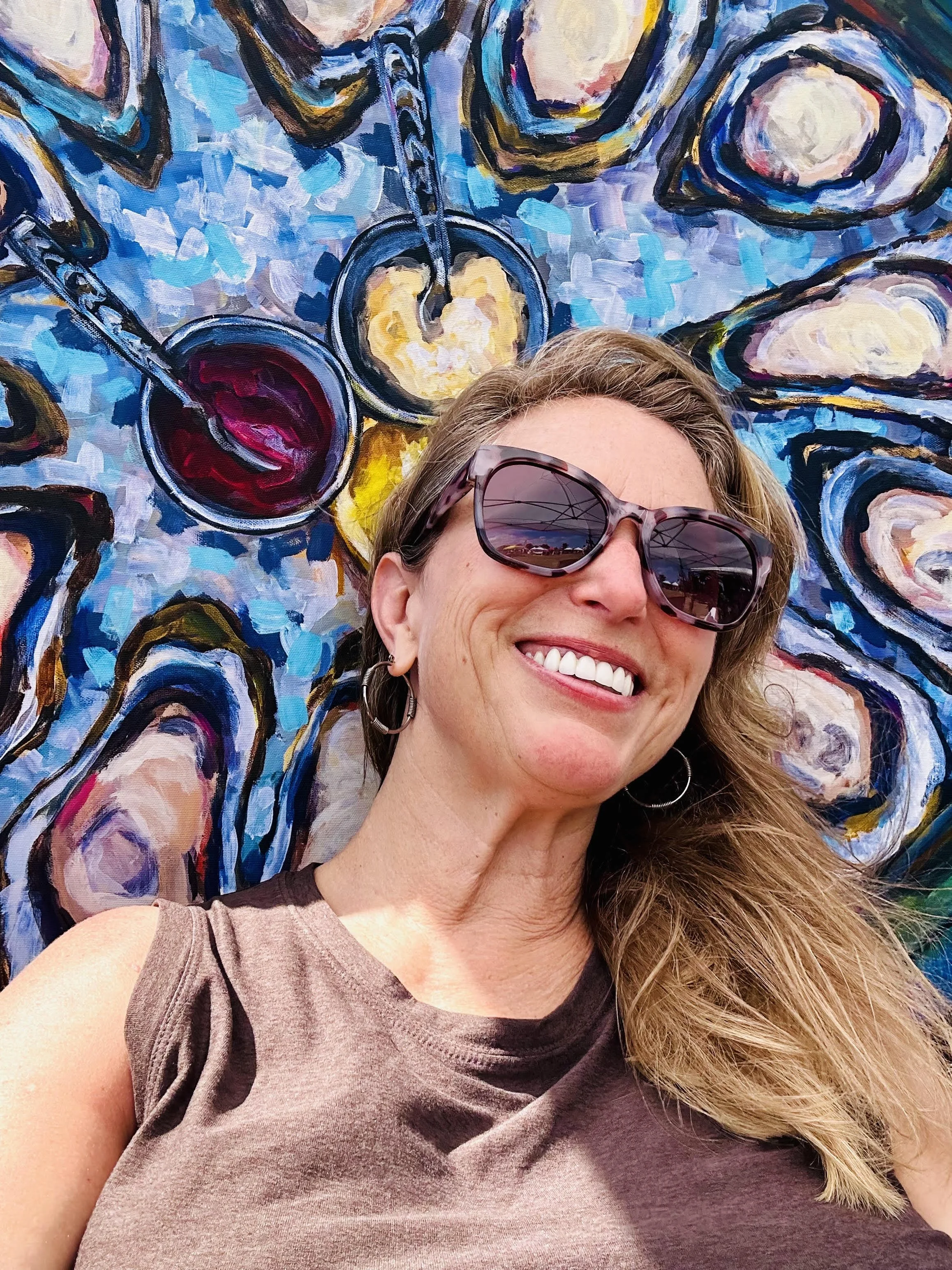 Artist Heather Donis laying on mural smiling with sunglasses