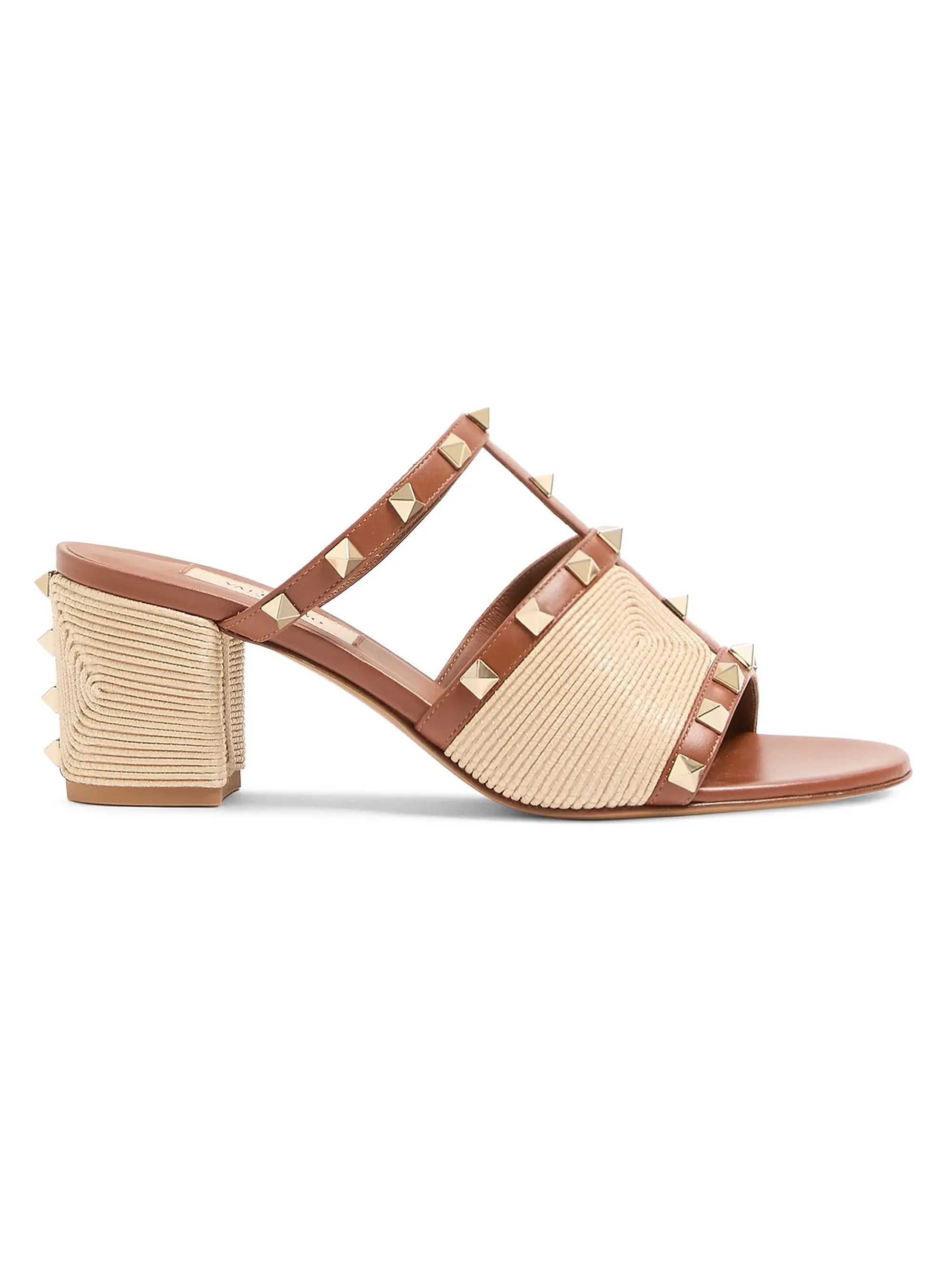 Close-up of a tan and beige high-heeled sandal with studded straps and a block heel, isolated on a white background.