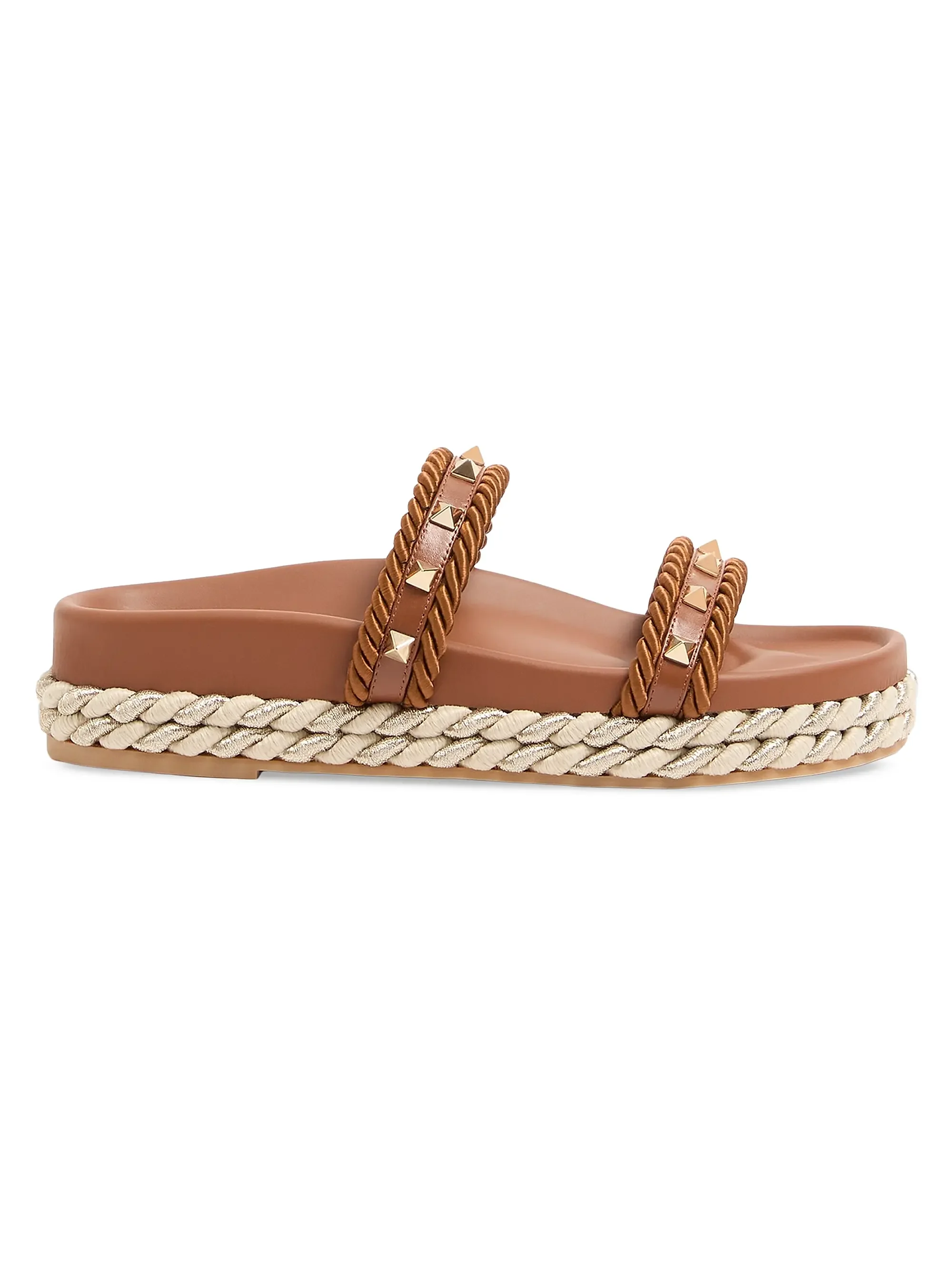 A tan-colored sandal with braided straps decorated with small gold studs and a thick braided sole.