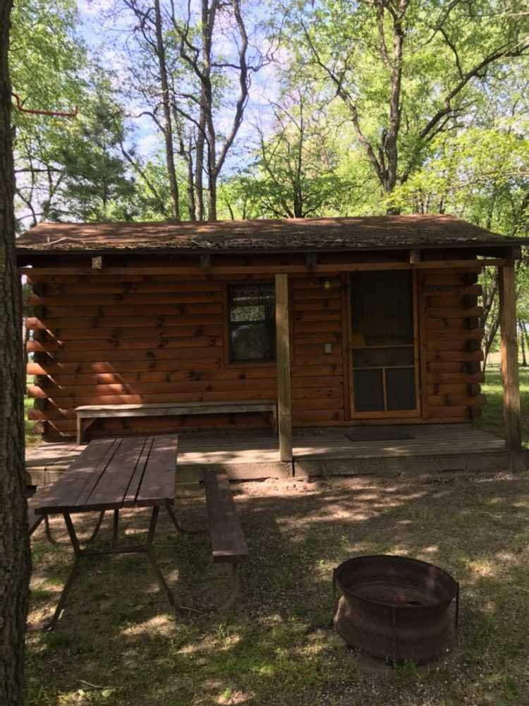 Primitive log cabin with a picnic table and fire pit