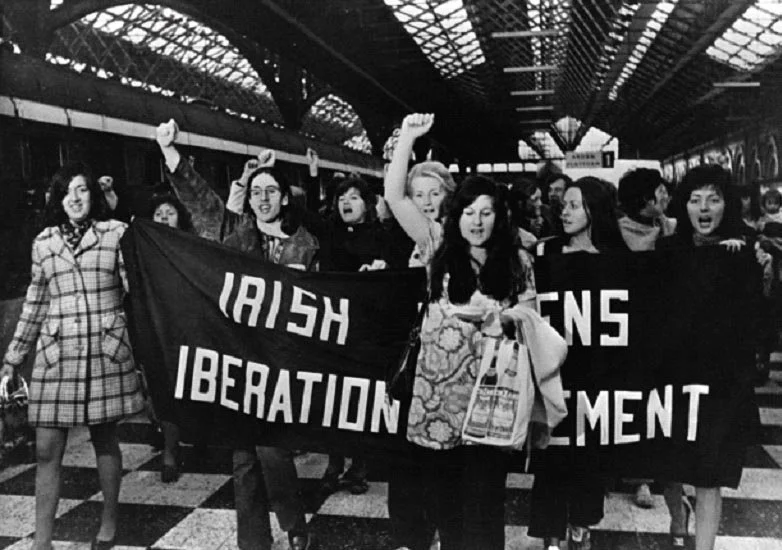 Photograph of Irish women marching and holding a protest banner as part of the contraceptive train protest, 1970s