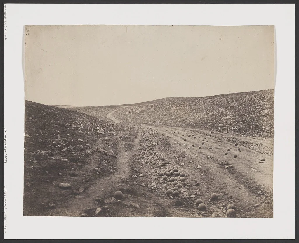 Black and white image of abandoned valley, except for scattered cannonballs.