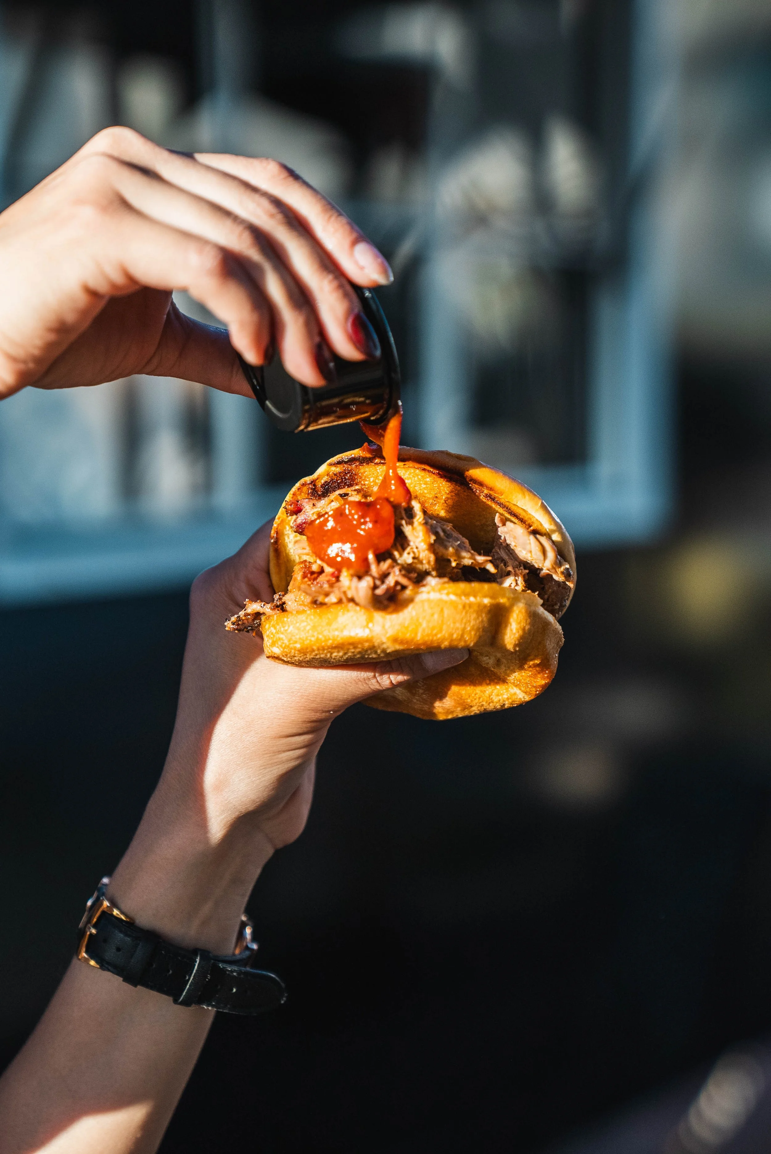 BBQ sandwich from 3 Mile BBQ with sauce being poured at NEEP Collective in El Paso
