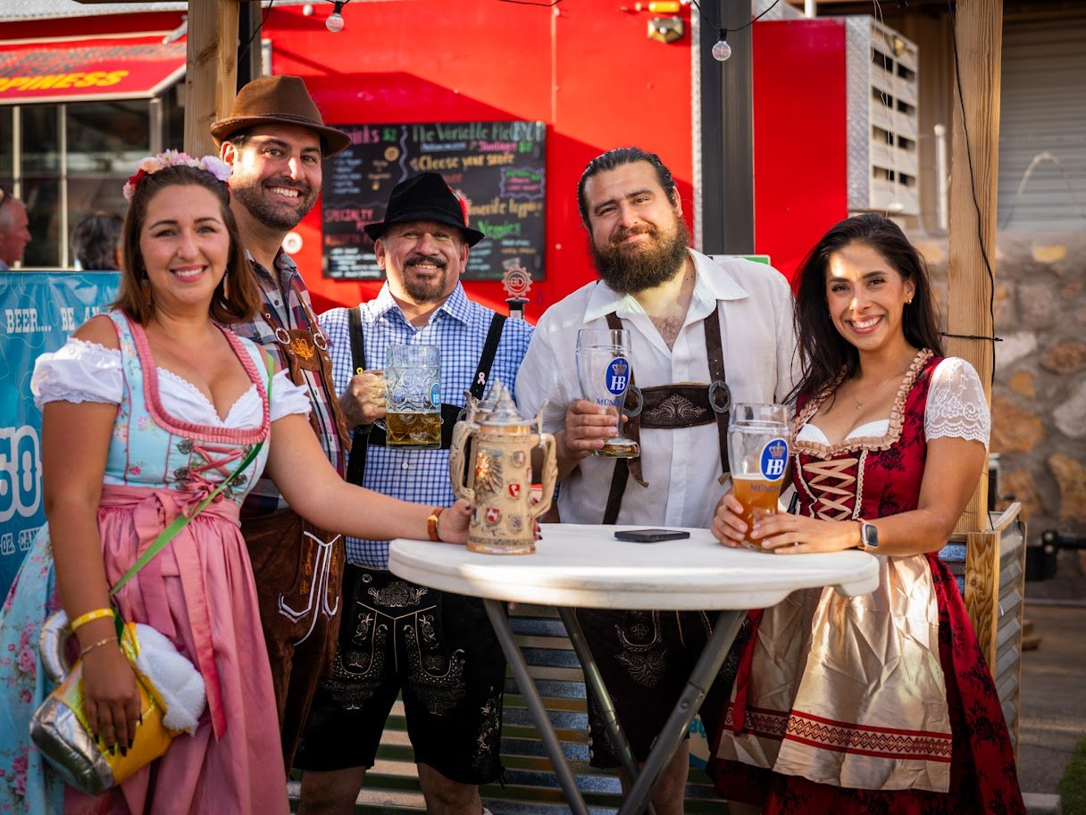 Guests celebrating Oktoberfest with beer steins at NEEP Collective in Northeast El Paso
