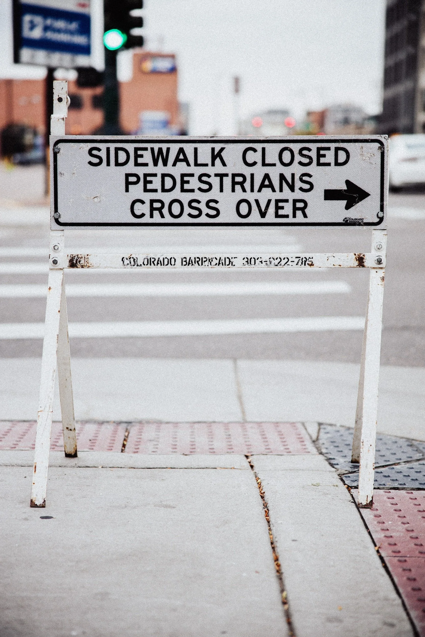 Construction sign that reads: "sidewalk closed pedestrians cross over" and an arrow pointing right.