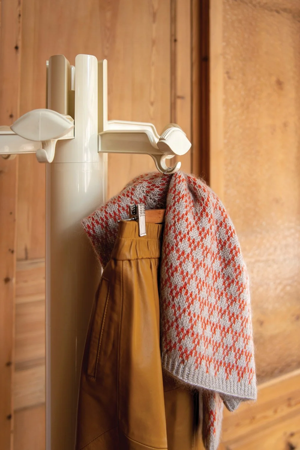 Vintage coathanger with knitted cardigan by Anne Ventzel and a modern leather skirt in front of wooden sliding doors for KOEL Magazine.