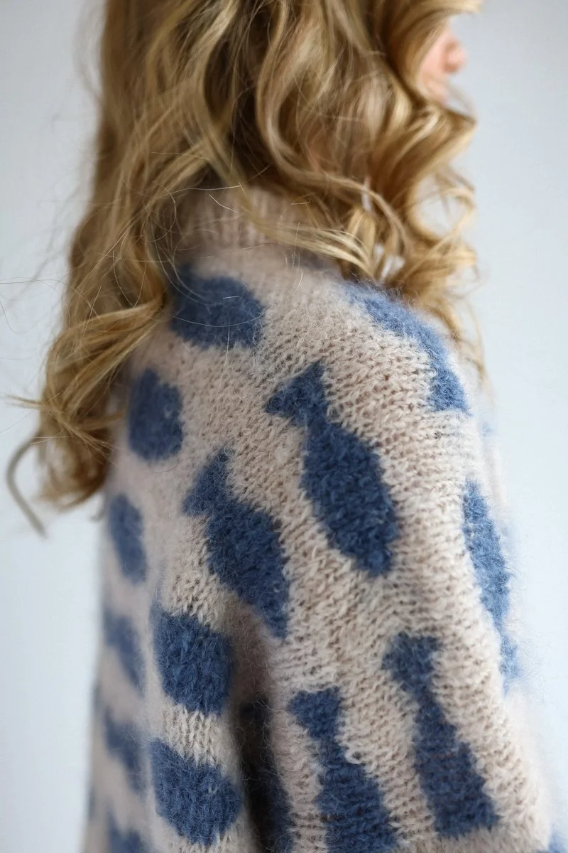 Woman wearing a handmade knitted sweater with blue dot pattern, close up of knitwear detail is fish pattern