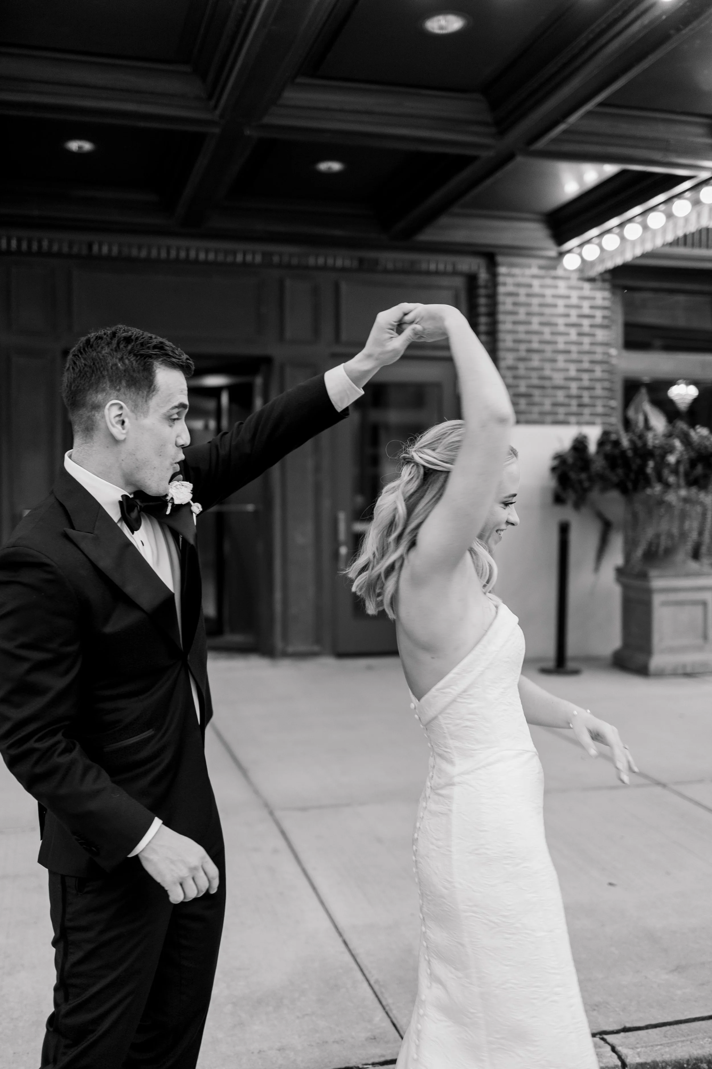 A black and white photo of a dancing couple, with the man in a tuxedo and the woman in a wedding dress, dancing outside Hotel Northland.