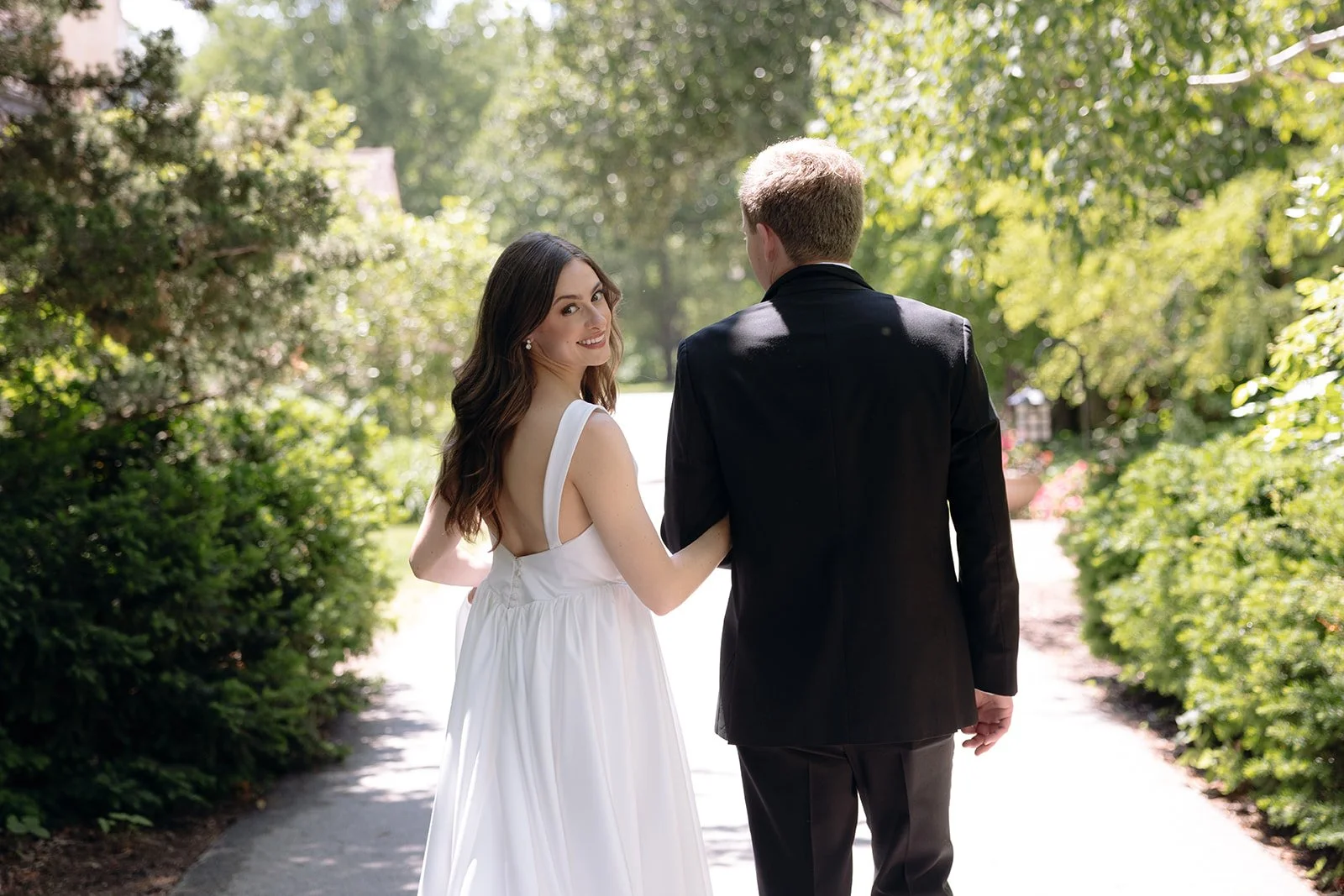 Bride and groom walking on the paved path at the Paine Art Center.