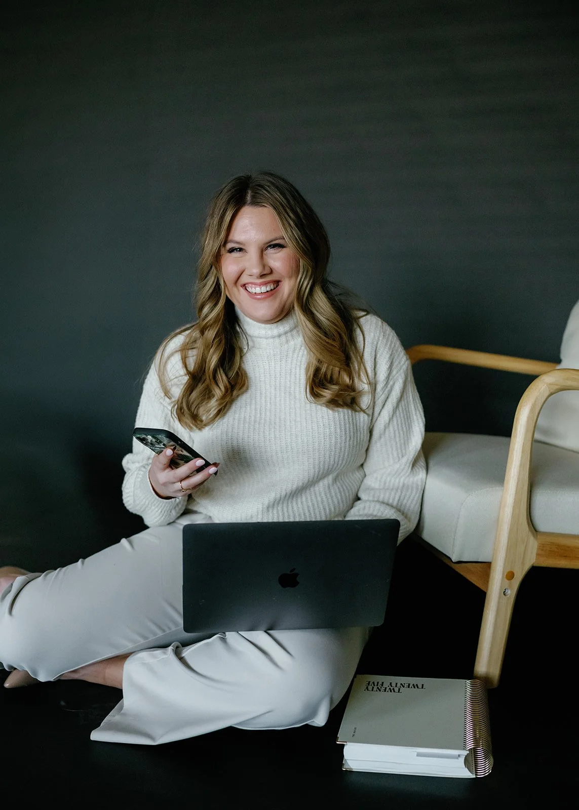 A Wisconsin wedding planner holding her cell phone and computer.