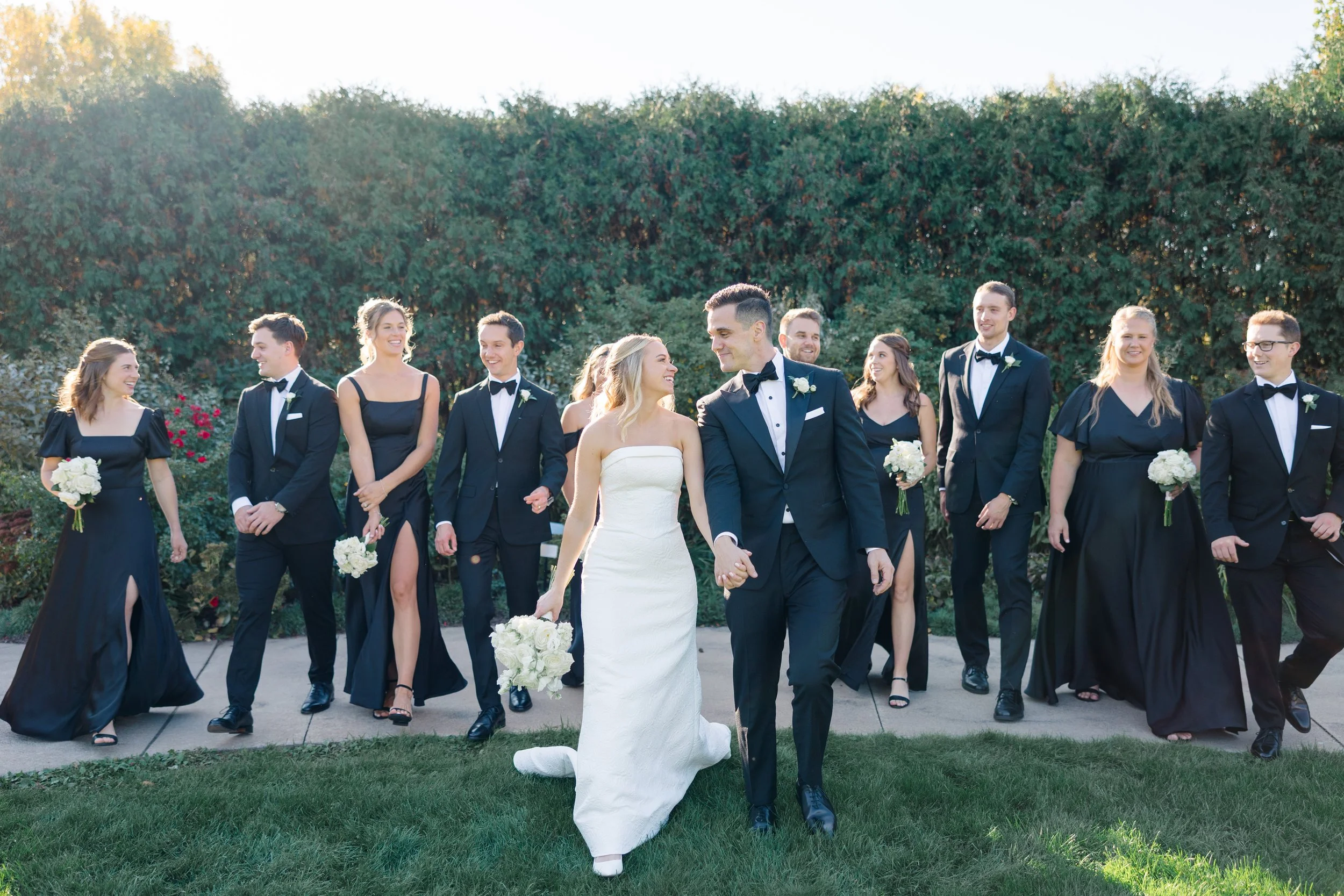 A group of people, including a bride and groom, walking in the Kress Oval Garden at Green Bay Botanical Garden.