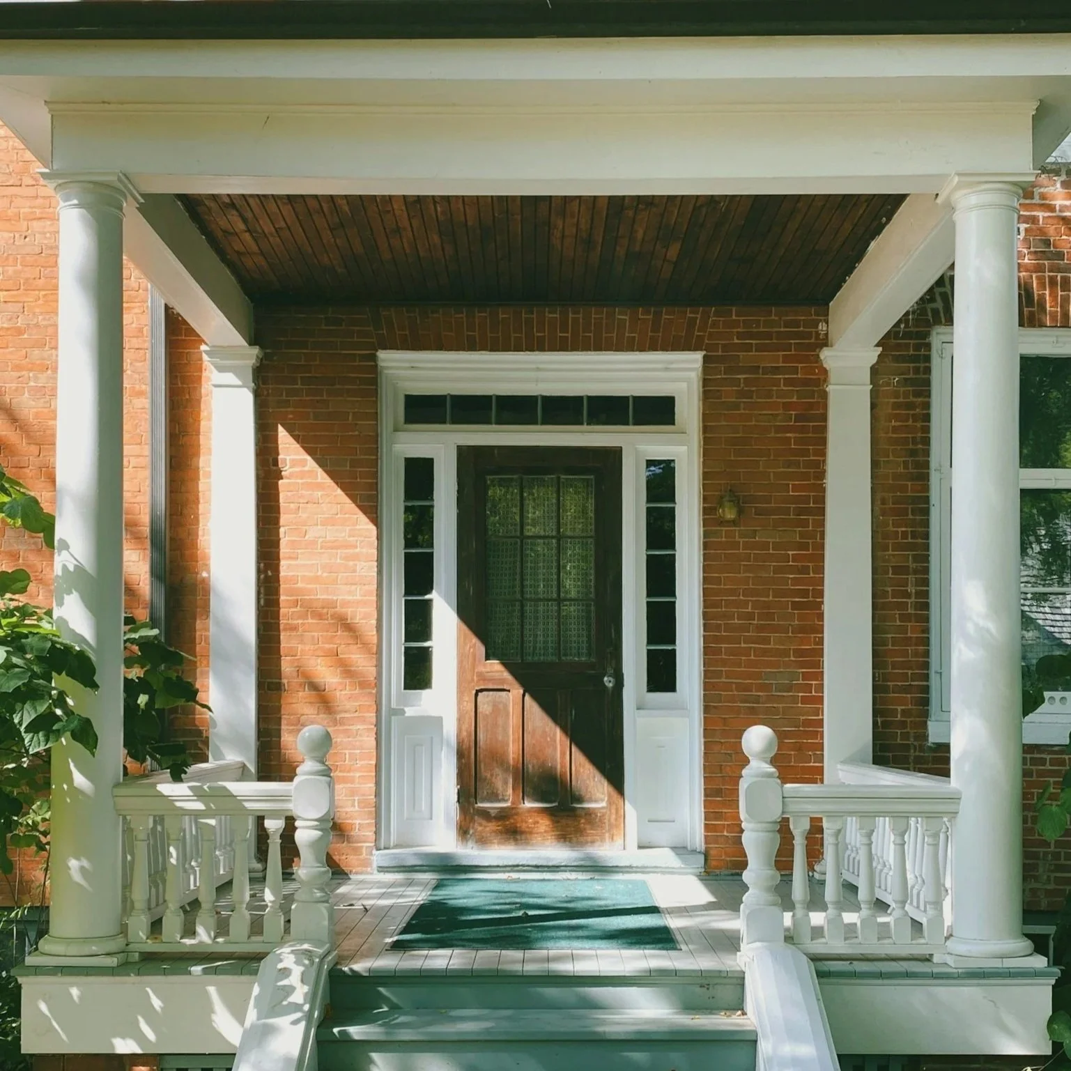 Dark walnut front door on a brick house with a covered porch