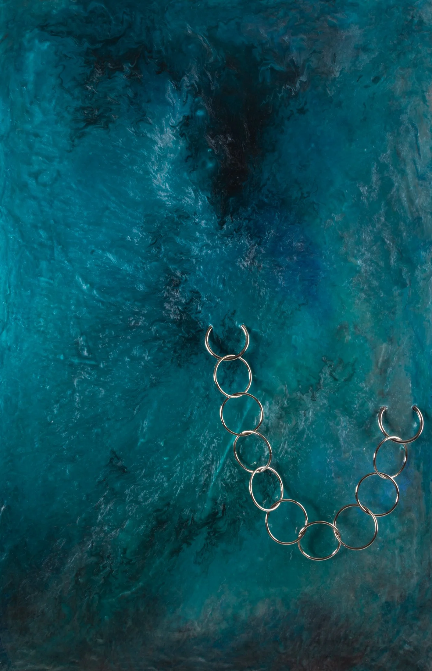 Blue and teal swirling water with metal rings in the foreground.