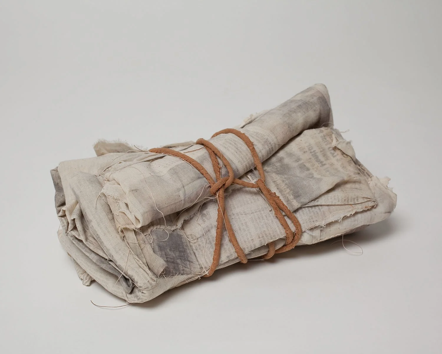 "Bundle", 2009, Newspaper print on muslin, cord, thread, 10 x 5 x 3 inches