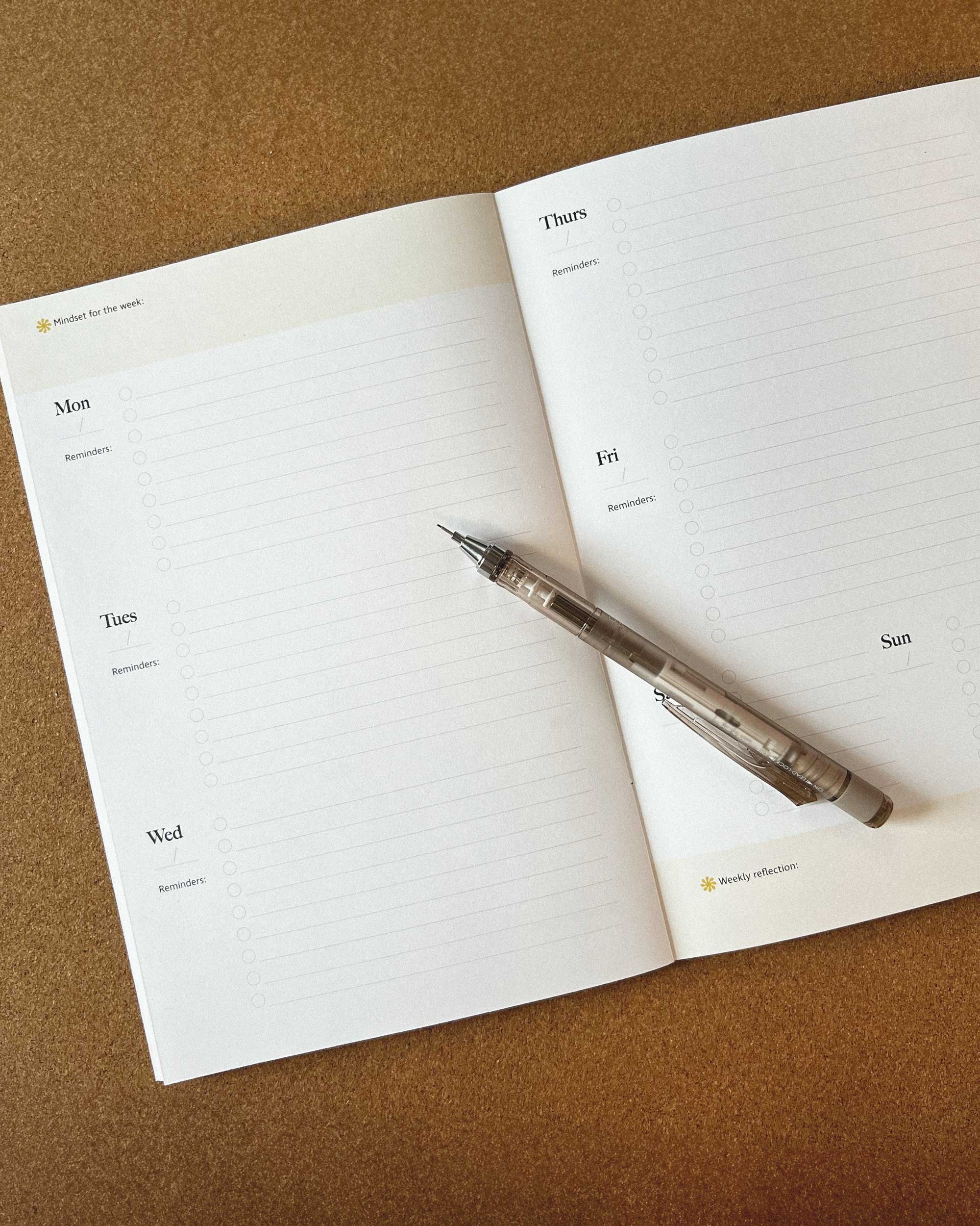 open planner on desk with cork board
