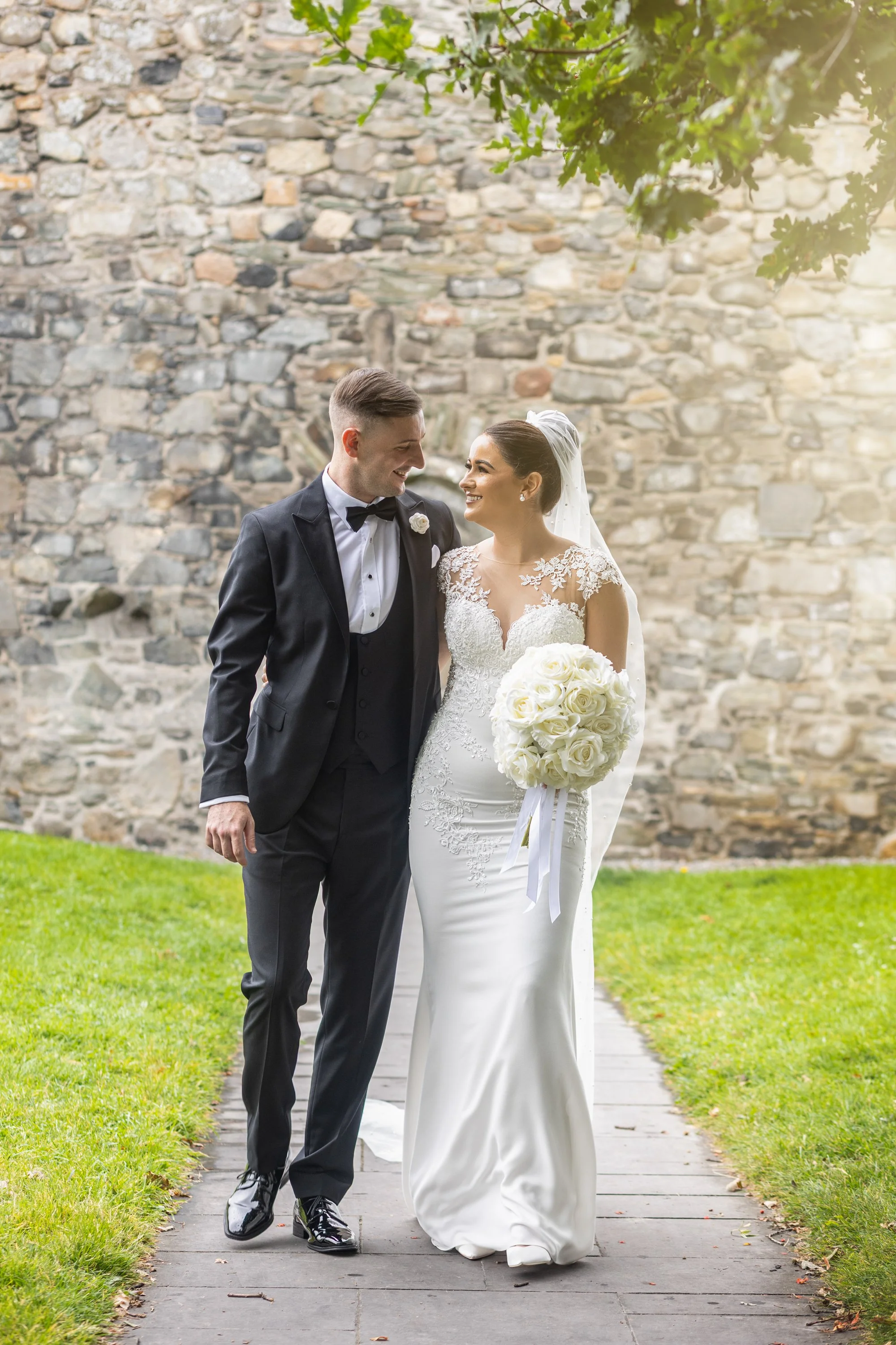 A couple sitting on a sandy beach near the water, facing each other and enjoying each other's company under a cloudy sky.